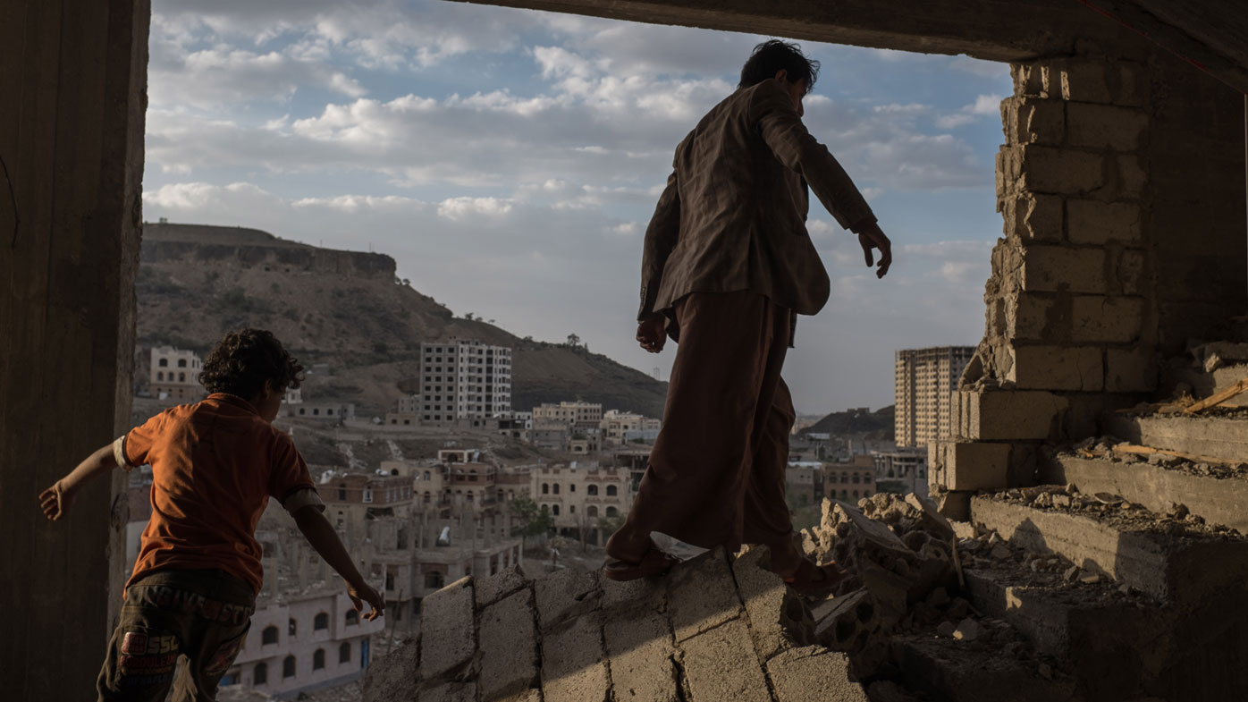 A man and a boy walk a war torn staircase in Yemen.