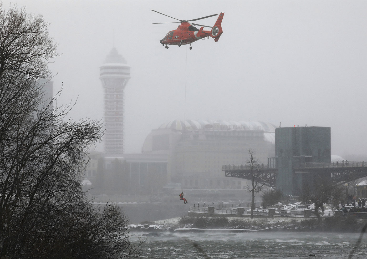 A US Coast Guard rescue diver is lowered toward the vehicle lodged in the water at the brink of Niagara Falls.