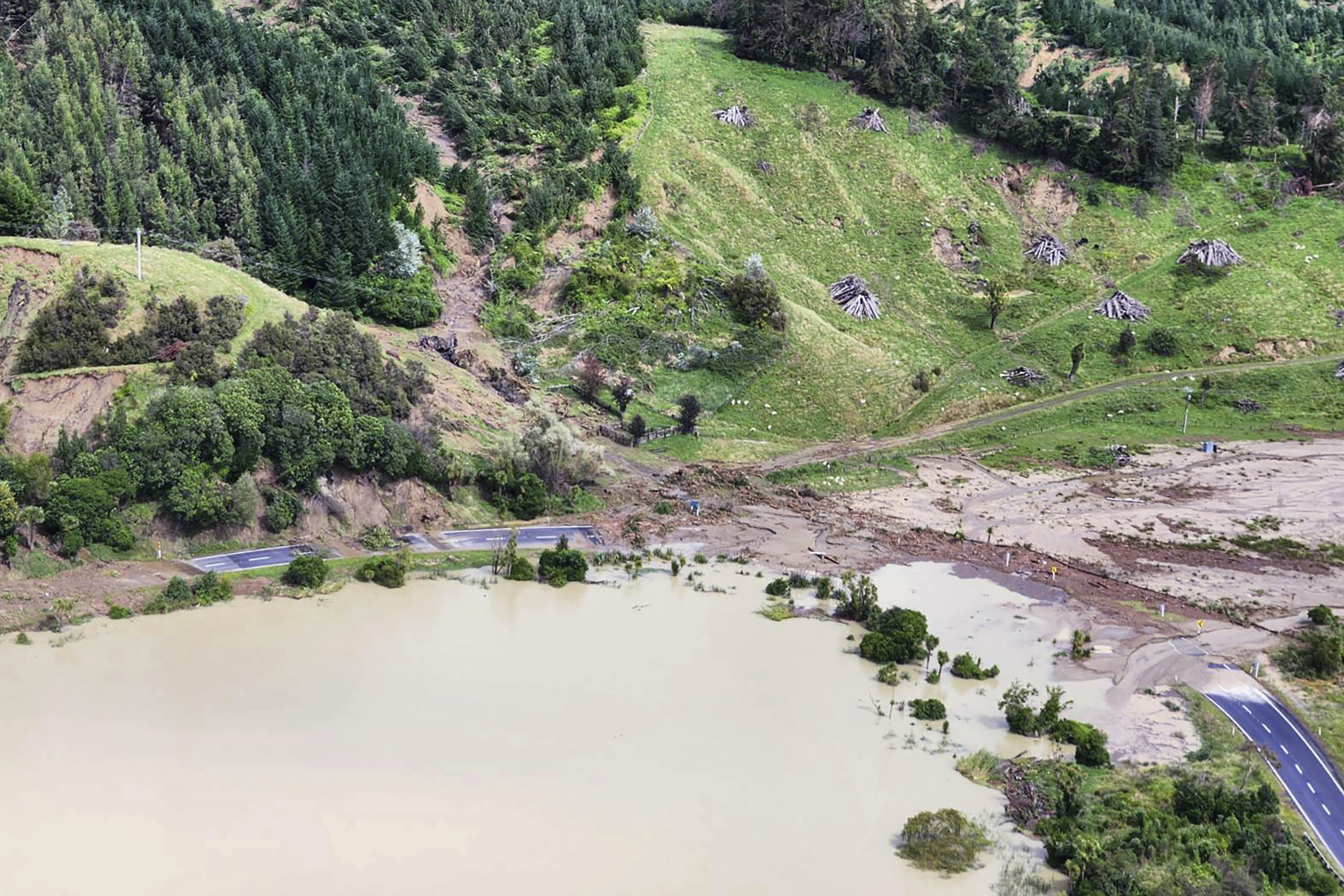 In this image released by the New Zealand Defence Force on Wednesday, Feb. 15, 2023, a road between Napier and Wairoa is washed out by flood water. The New Zealand government declared a national state of emergency Tuesday after Cyclone Gabrielle battered the country's north in what officials described as the nation's most severe weather event in years. (New Zealand Defense Force via AP)