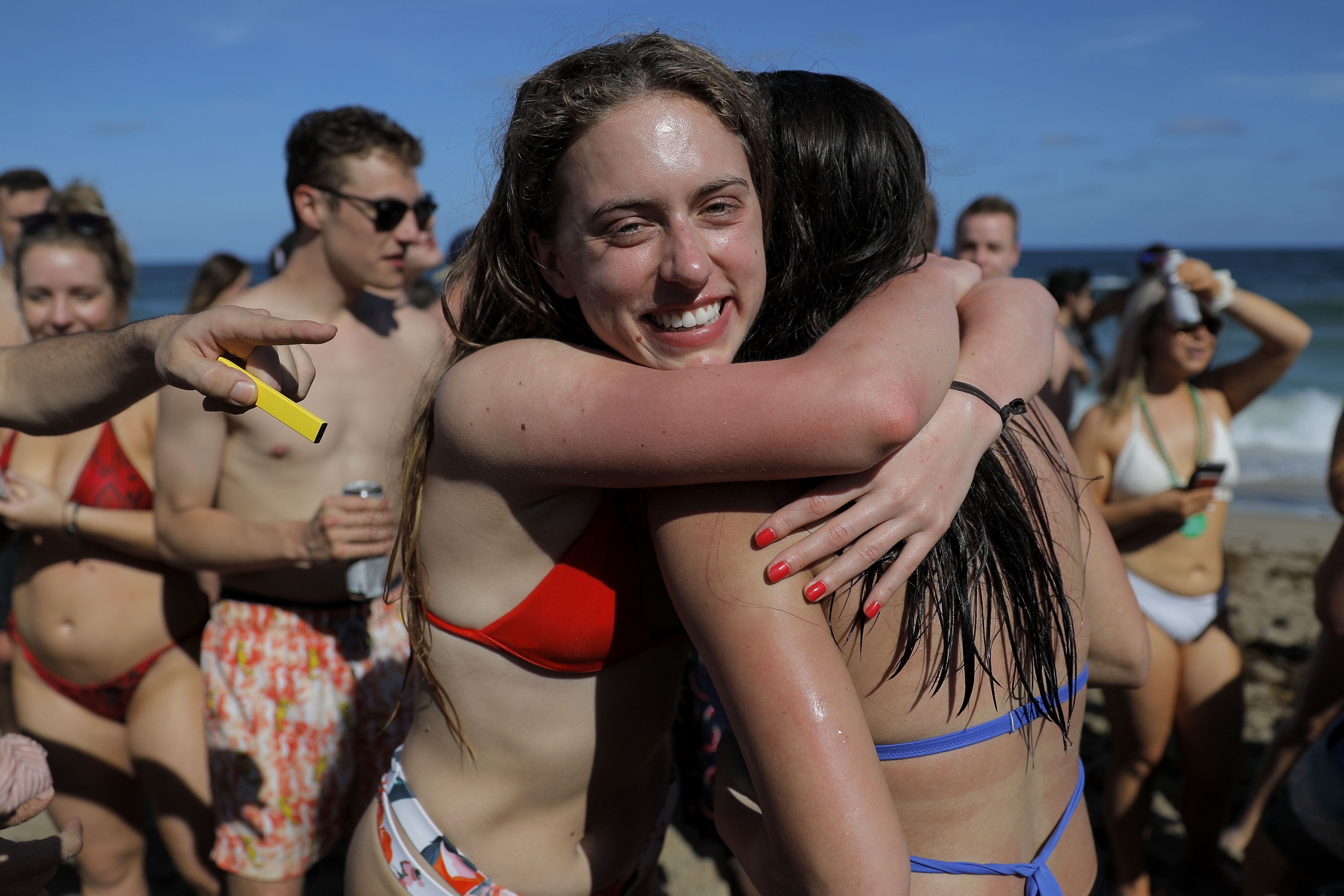 Two spring break revelers hug while partyng in a large crowd on the beach, Tuesday, March 17, 2020, in Pompano Beach, Fla. 