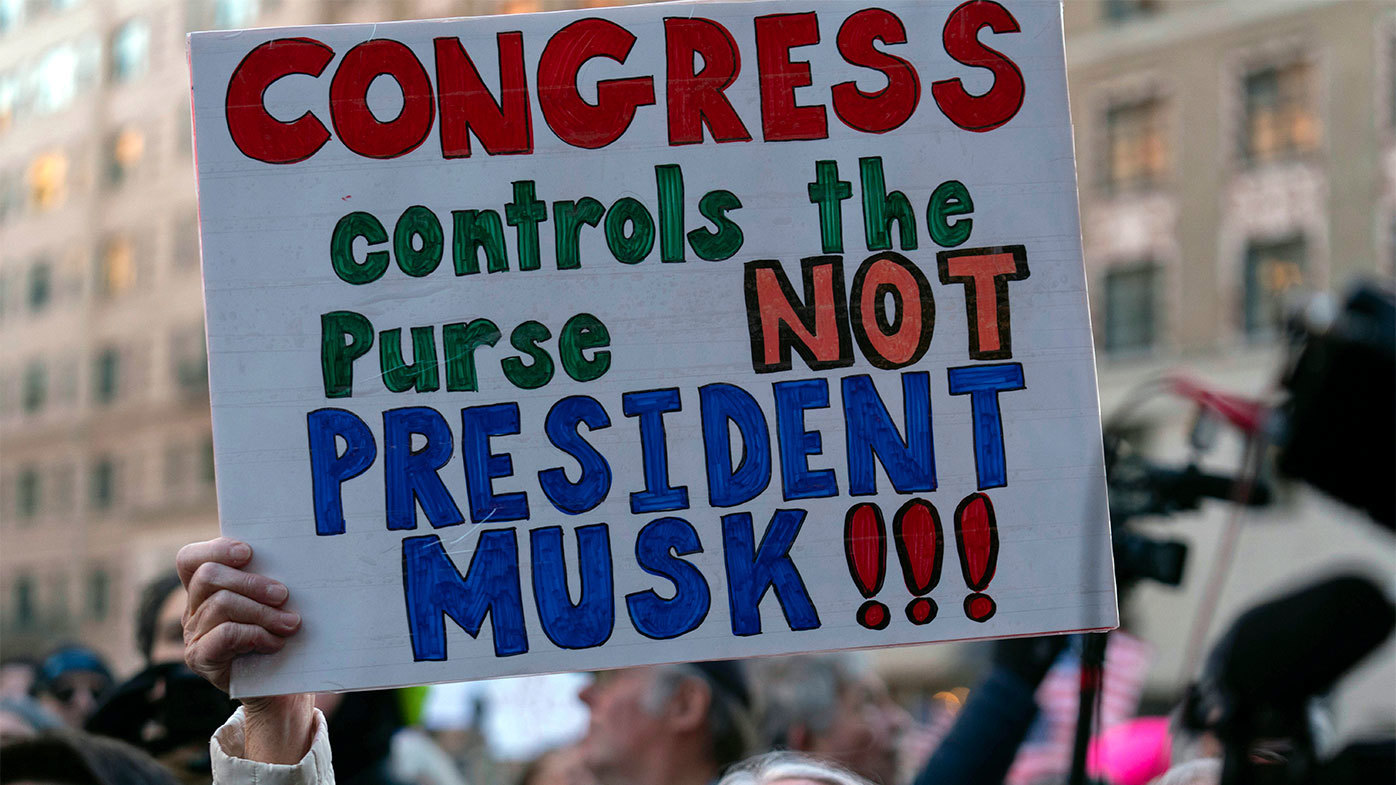 People rally as they listen members of congress speak during a rally against Elon Musk outside the Treasury Department.