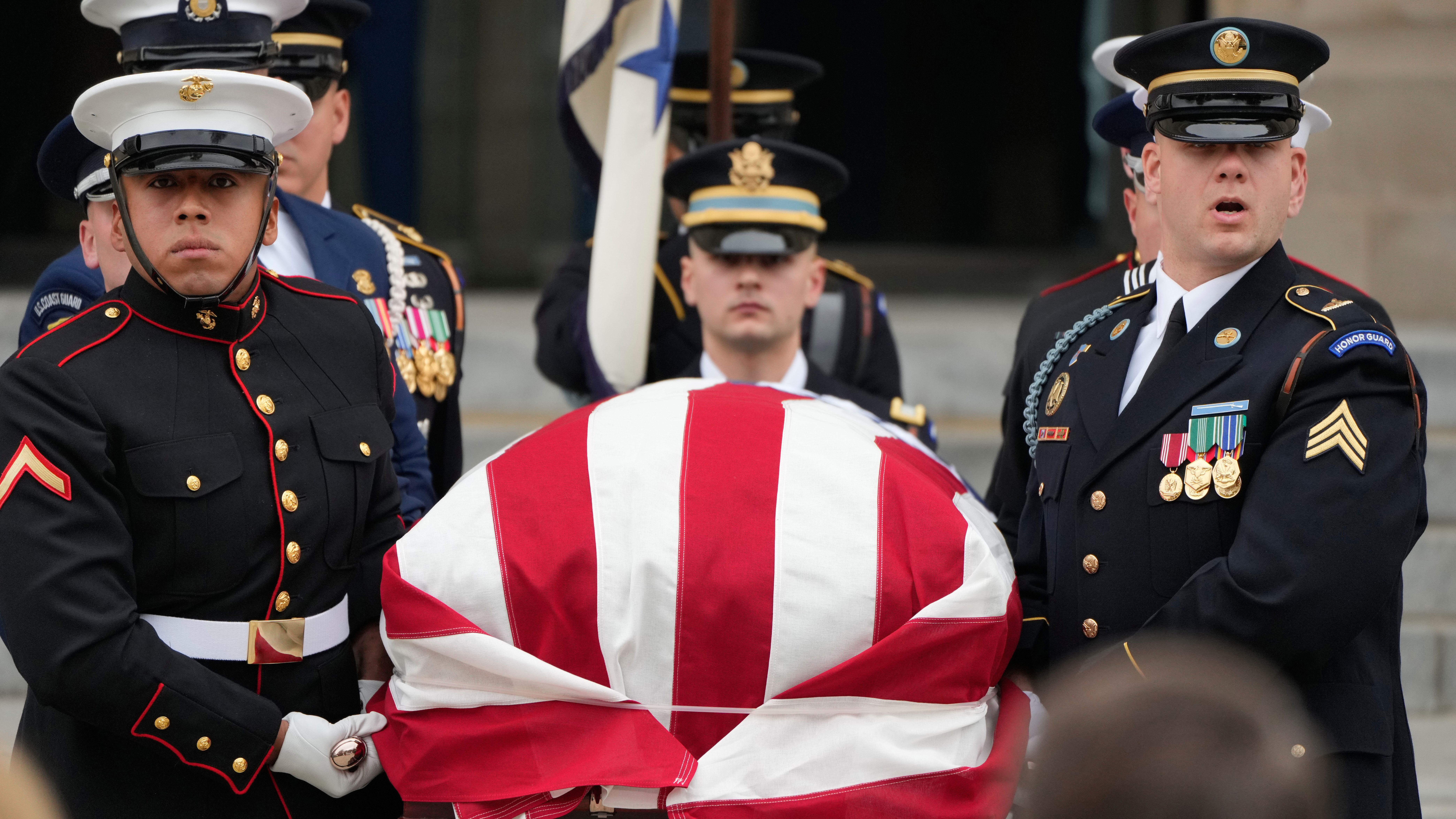 A joint services body bearer team carries the flag-draped casket of former Vice President Dick Cheney out of the Washington National Cathedral.