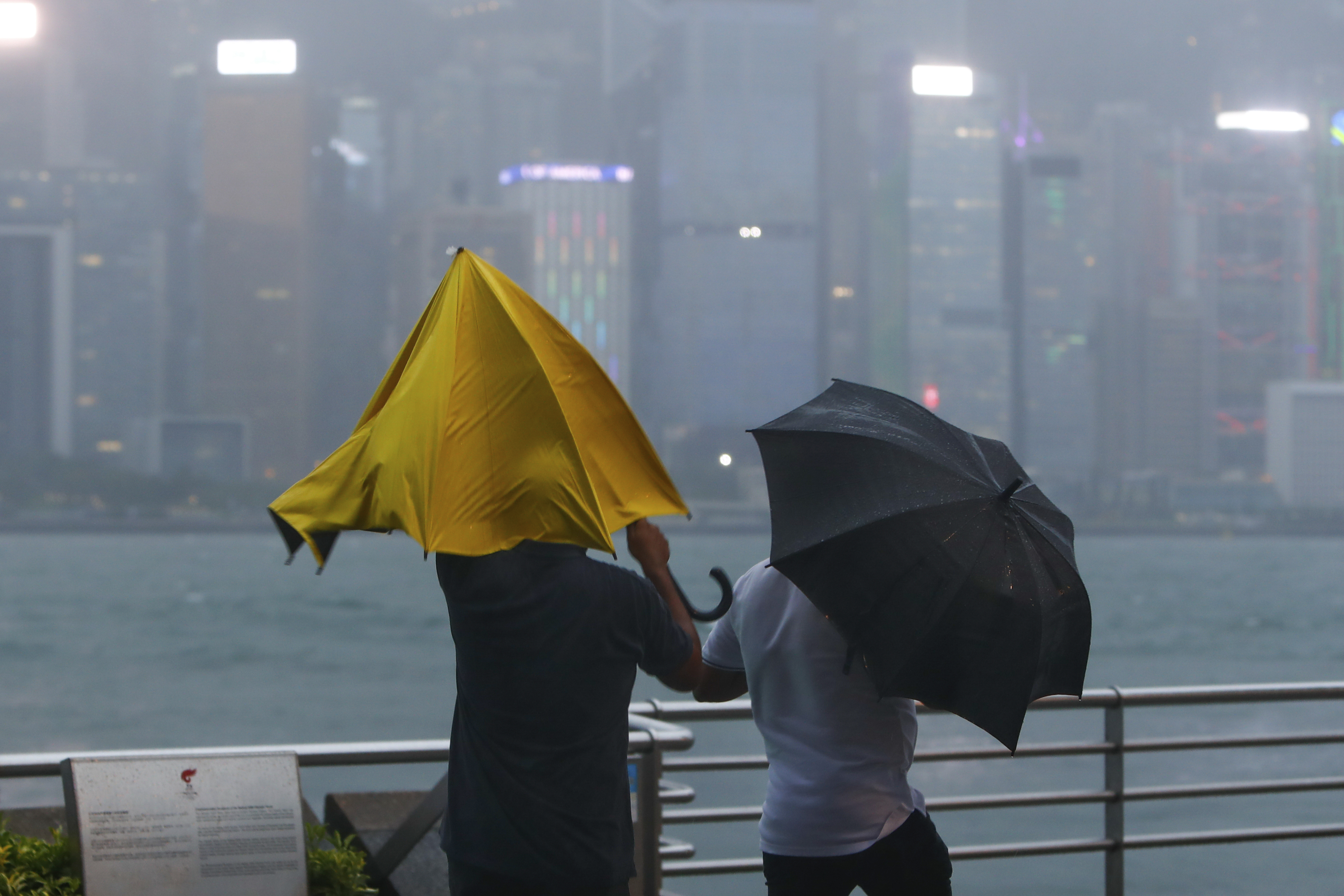 People with umbrellas struggle against the strong wind and rain brought by super typhoon Saola in Hong Kong, on Friday, Sept. 1, 2023. 