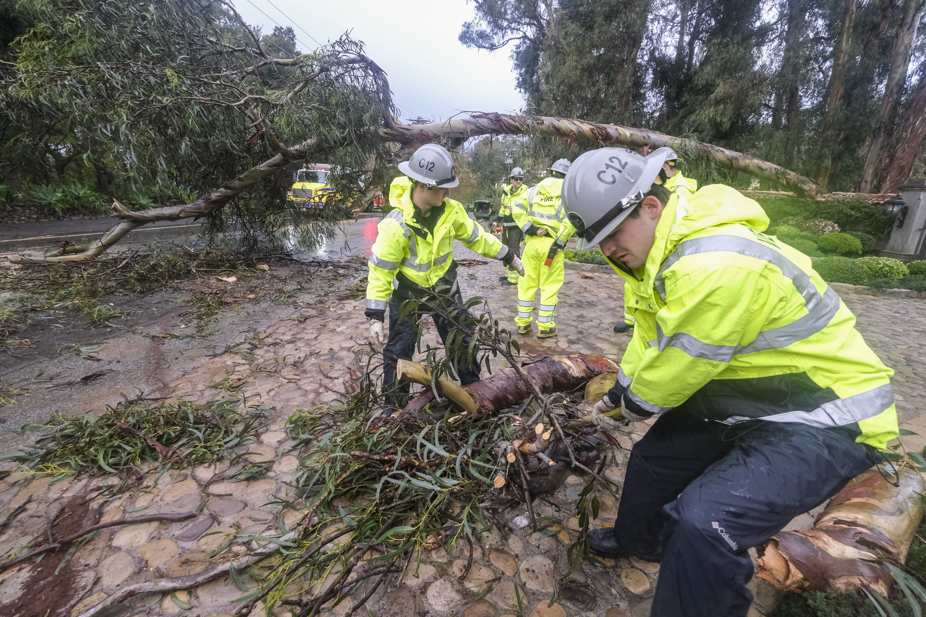 Firefighters clear away a fallen tree in Montecito, Calif., Tuesday, Jan. 10, 2023.