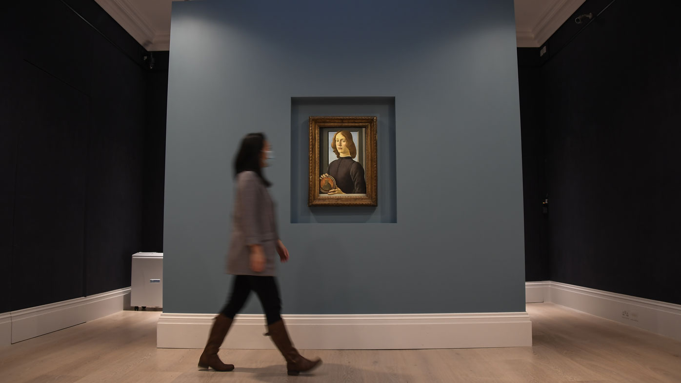 A member of the staff walks past the painting 'Young Man Holding a Roundel' by the Italian Renaissance painter Sandro Botticelli at Sotheby's, in London, Wednesday, Dec. 2, 2020