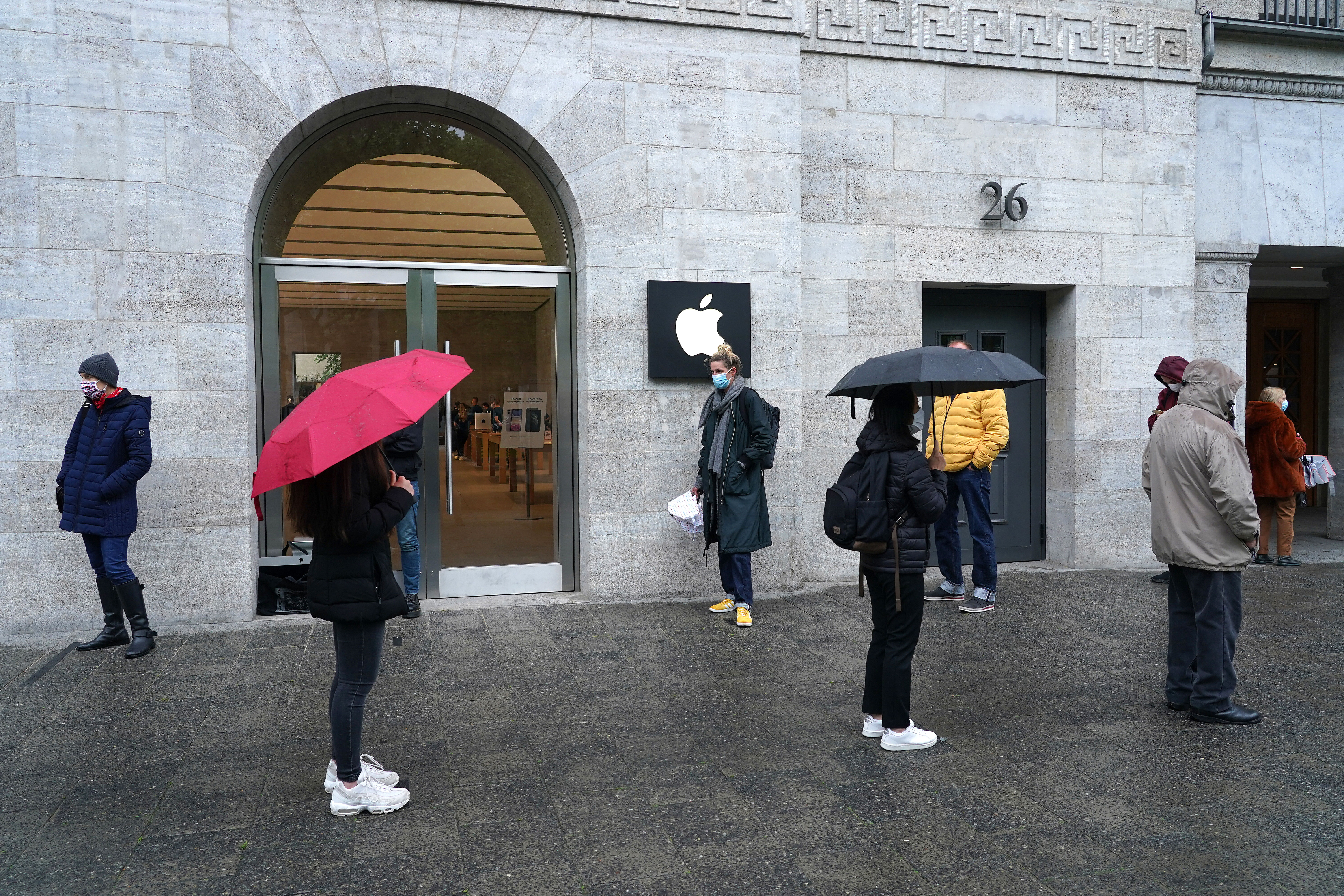 People stand in line and socially-distanced to enter the Berlin Apple store on the first day the store reopened since March