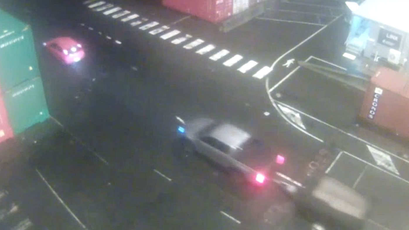 A red Holden Barina hatchback and a dark coloured utility drive through a holding yard in Strathfield South