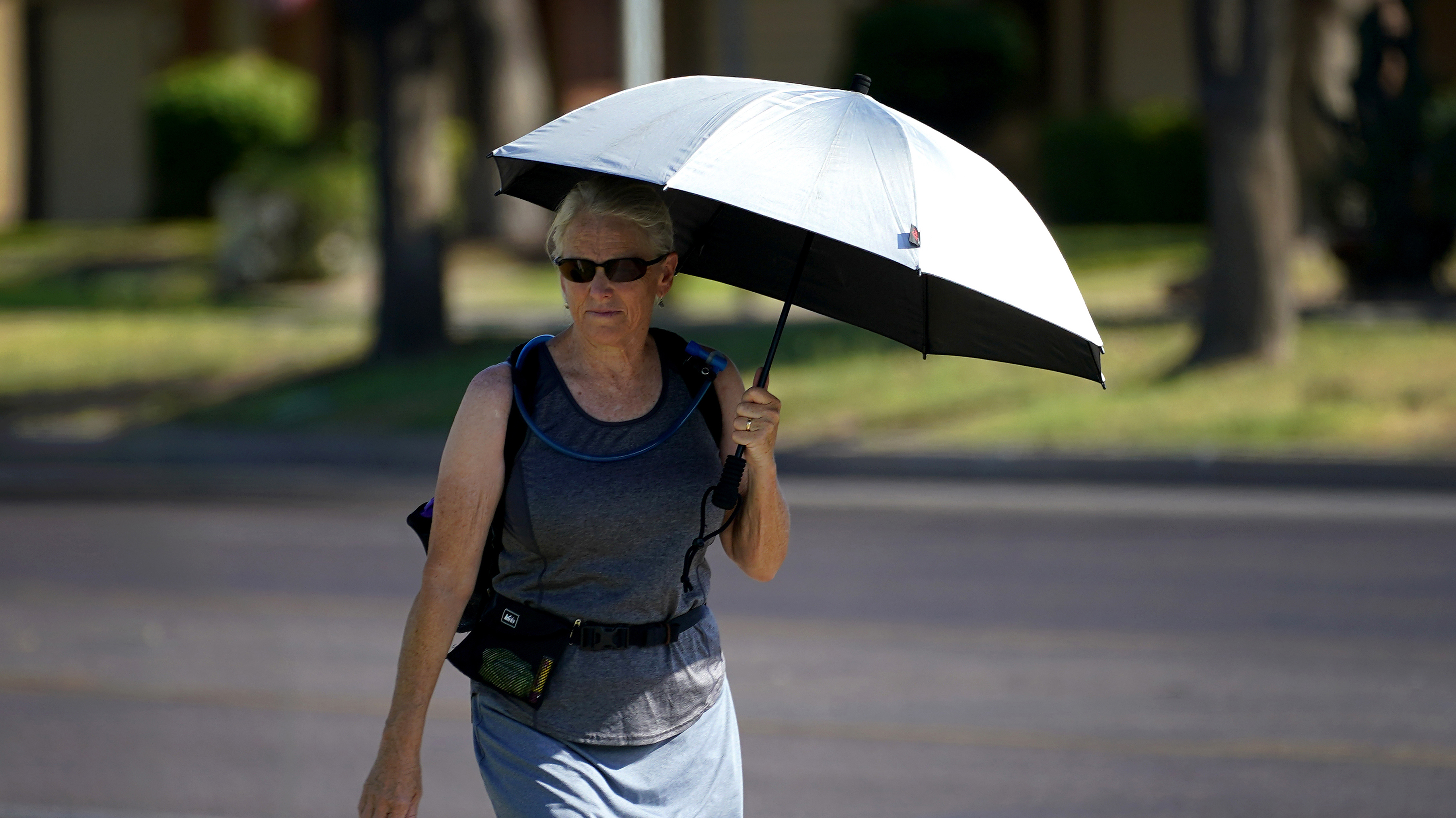 Una señora usa una sombrilla como sombra para combatir las altas temperaturas, en Phoenix, Arizona.