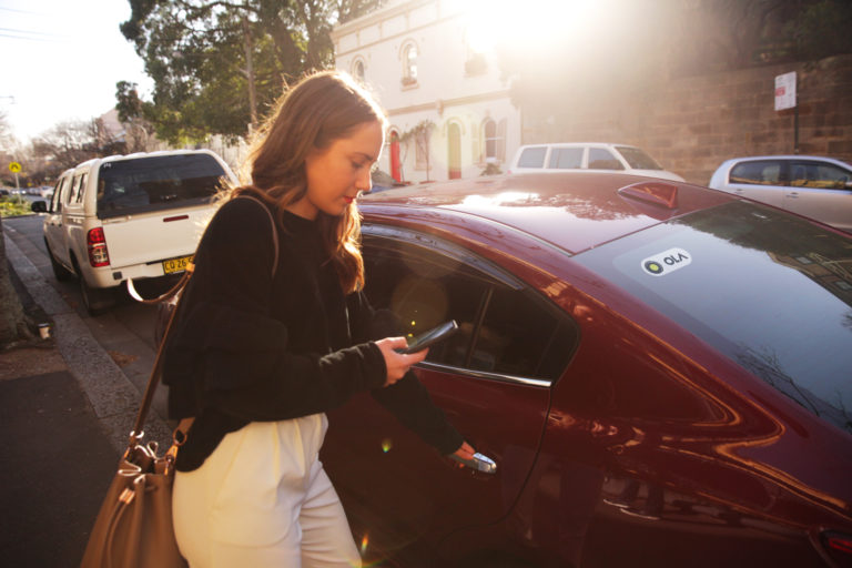 A woman using the Ola rideshare app.