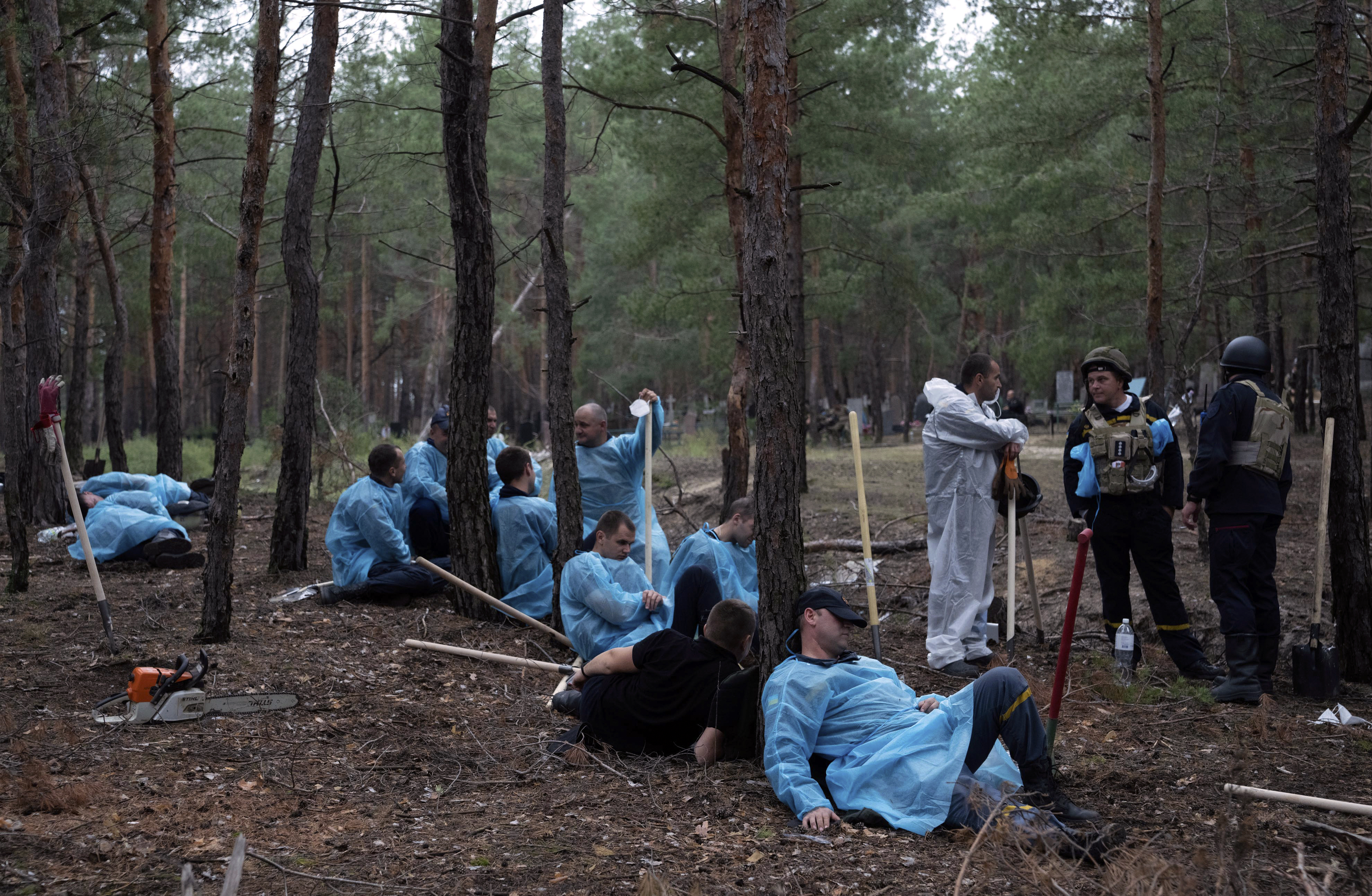 Emergency workers have a rest during the exhumation of bodies in the recently retaken area of Izium, Ukraine, Friday, Sept. 16, 2022. 