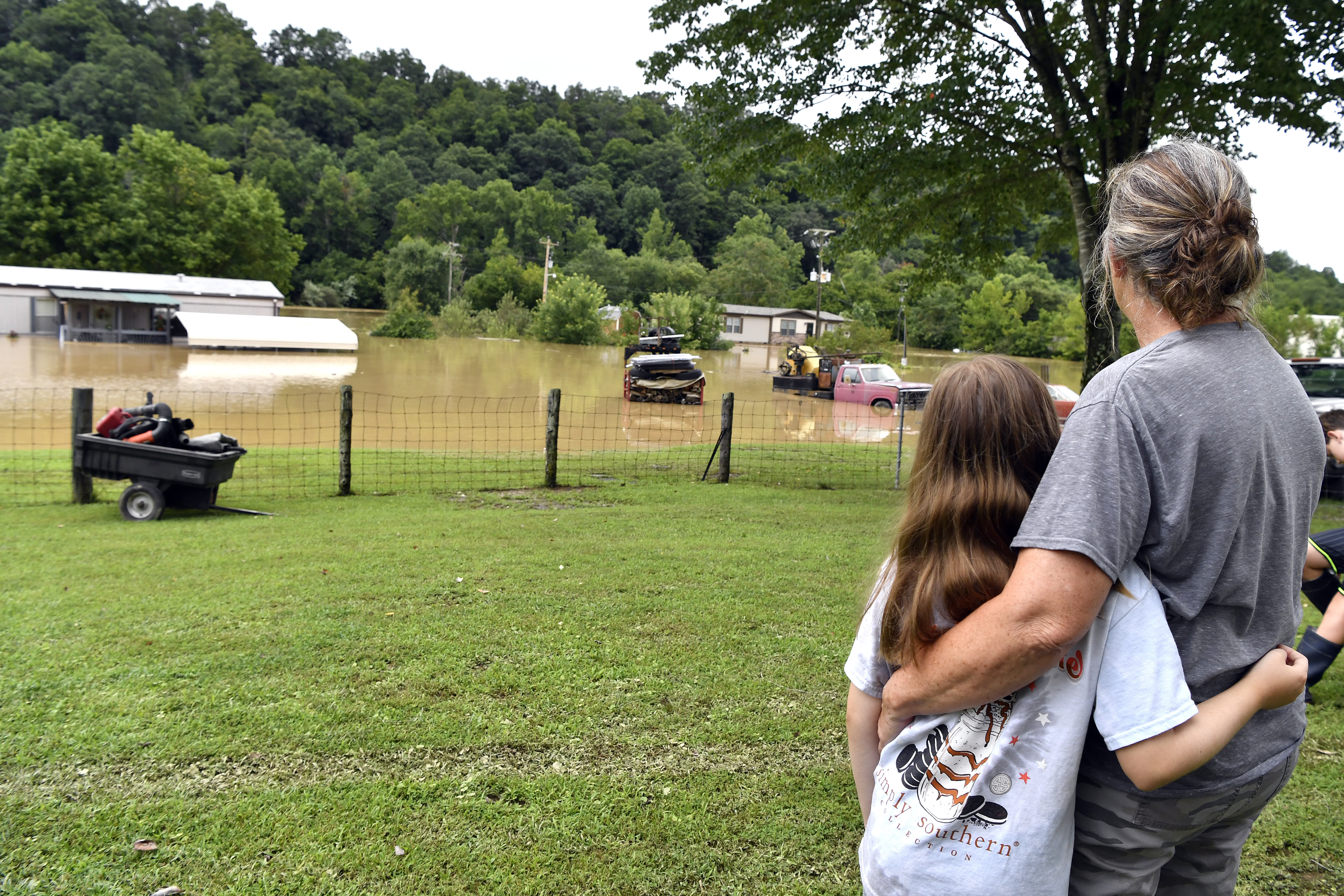 Bonnie Combs, right, hugs her 10-year-old granddaughter Adelynn Bowling watches as her property becomes covered by the North Fork of the Kentucky River in Jackson, Ky., Thursday, July 28, 2022. Flash flooding and mudslides were reported across the mountainous region of eastern Kentucky. (AP Photo/Timothy D. Easley)