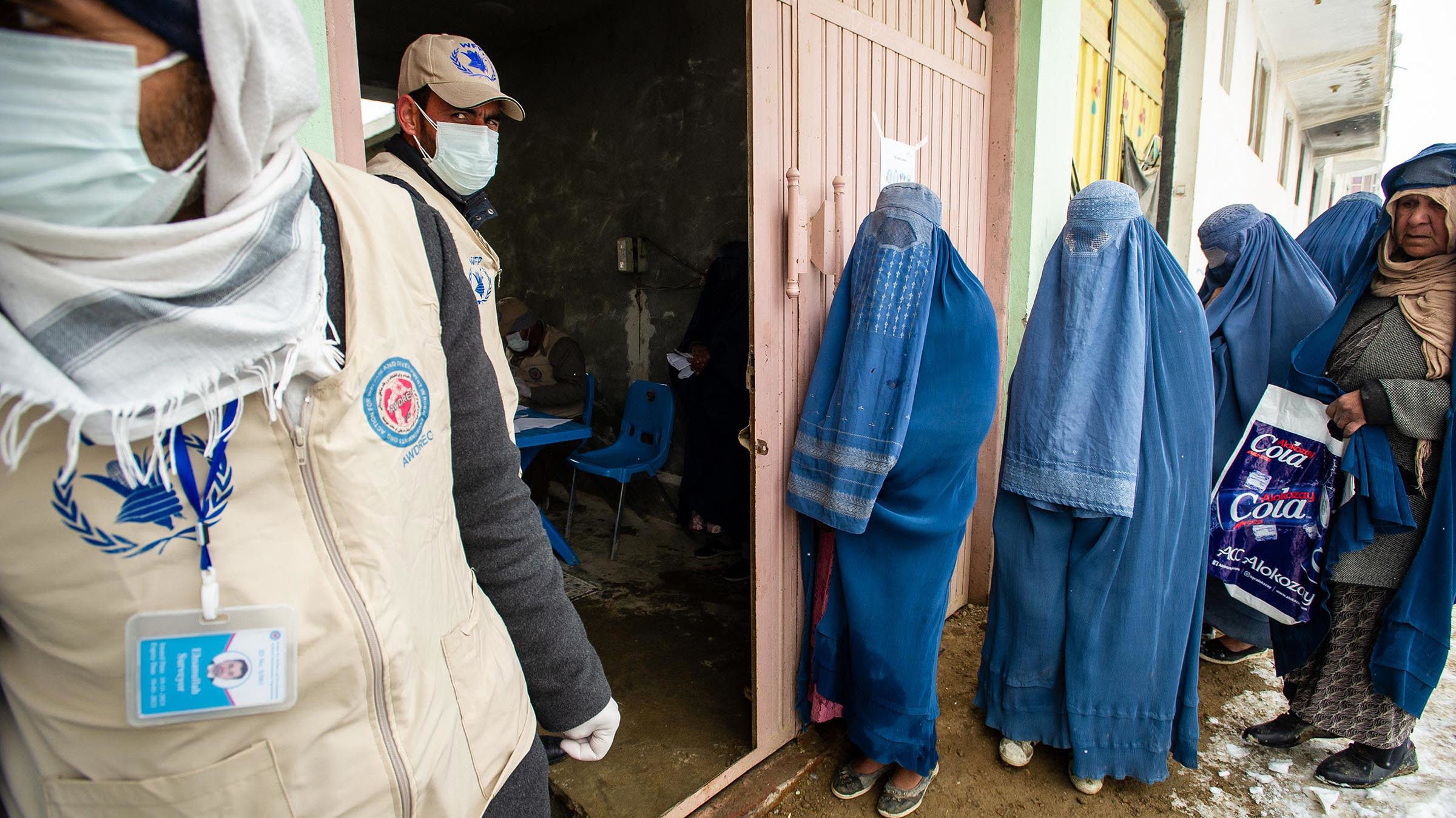 Las mujeres se alinean mientras el Programa de Alimentos Mundiales de la ONU distribuye una ración de alimentos mensual crítica, en gran parte suministrada por USAID, a 400 familias al sur de Kabul, Afganistán, en enero de 2022.