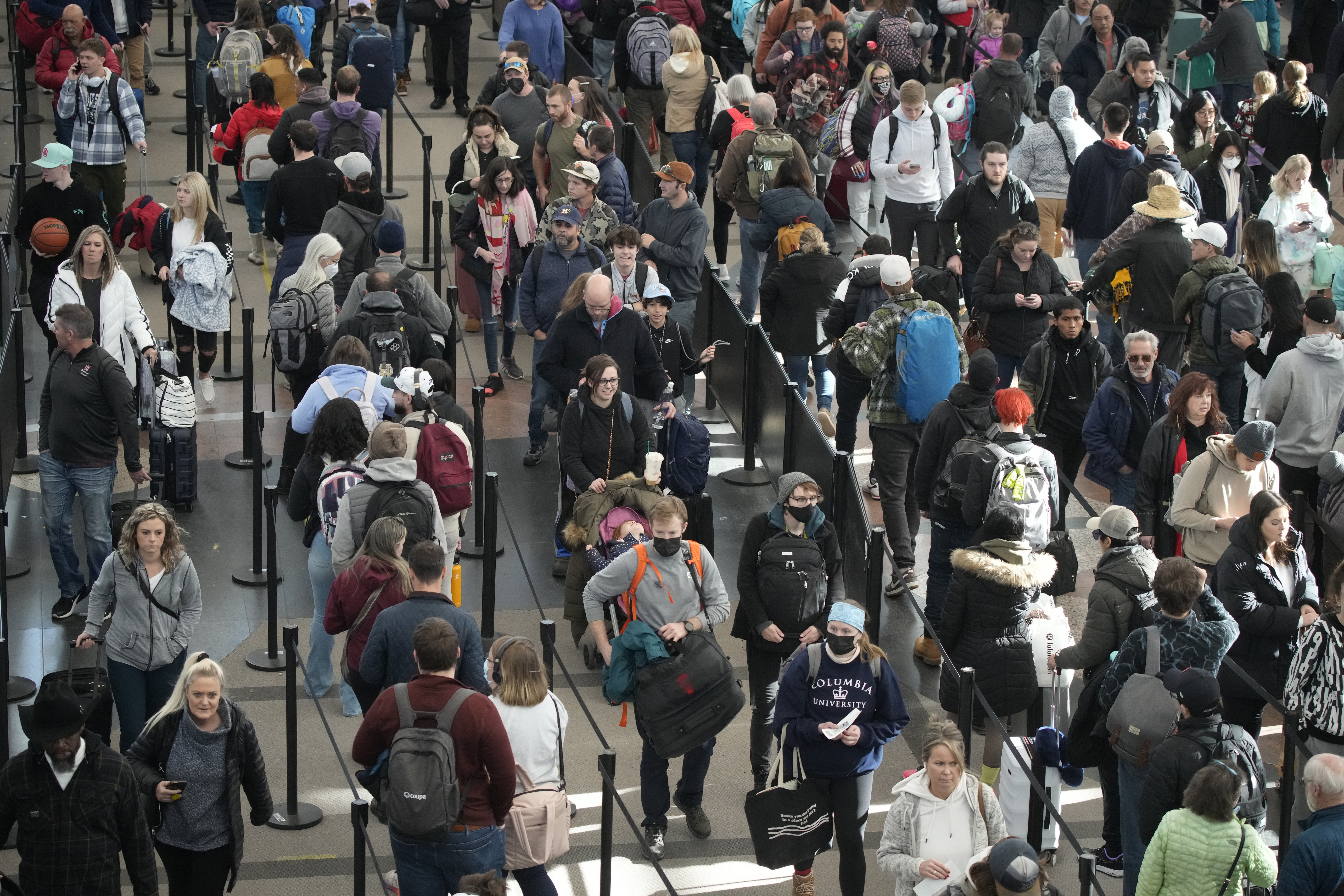 Travelers queue up to pass through the south security checkpoint in Denver International Airport after a winter storm swept over the country packing snow combined with Arctic cold, which created chaos for people trying to reach their destinations before the Christmas holiday, Friday, Dec. 23, 2022, in Denver. 