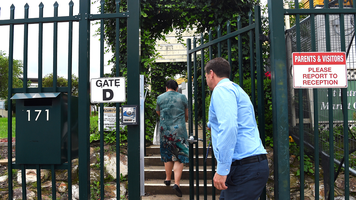 The deputy principal of St Patrick's Marist College in Dundas, Sydney opens the gate to a parent of a student