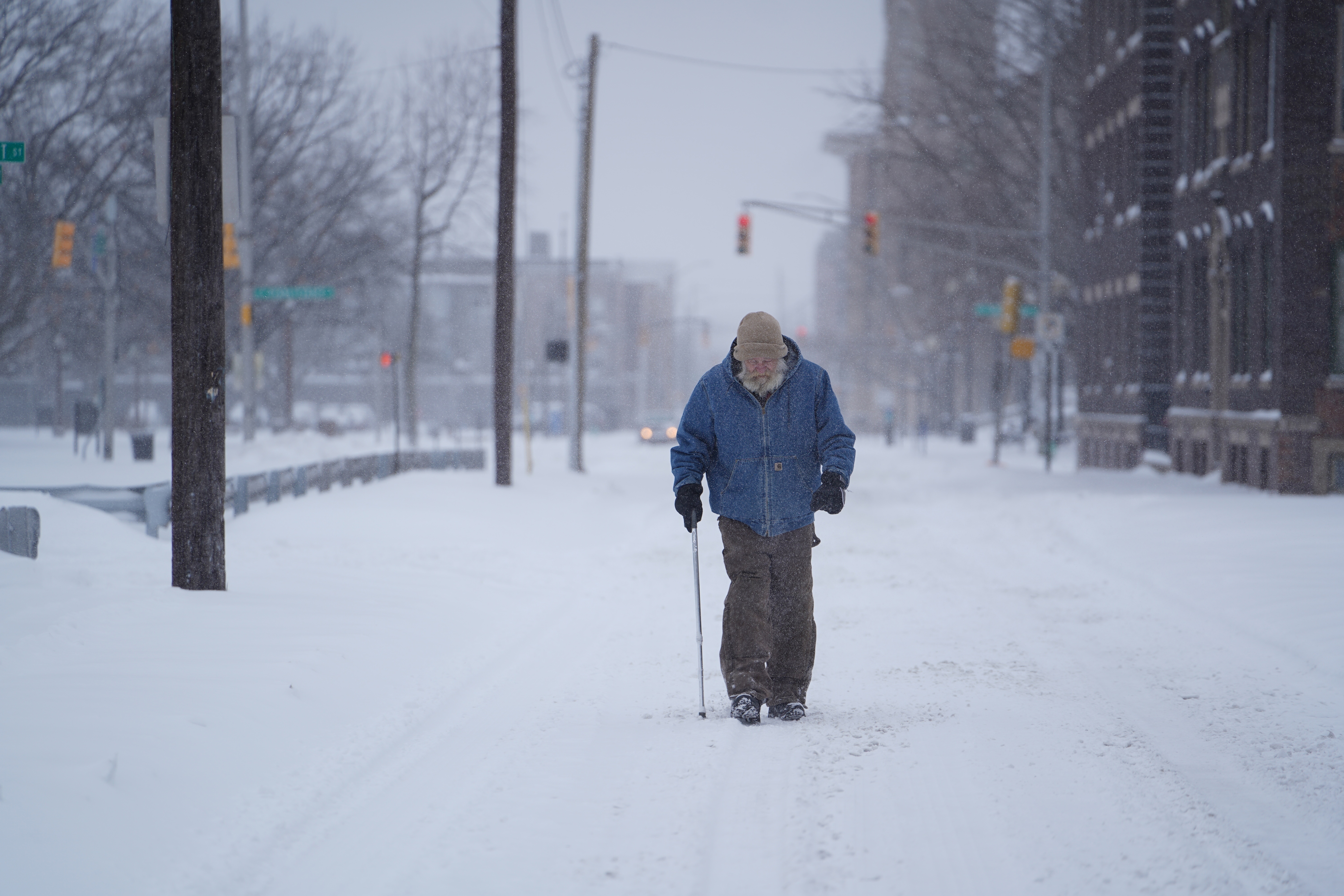 A man walks in the middle of a street during a snowstorm in downtown Indianapolis.