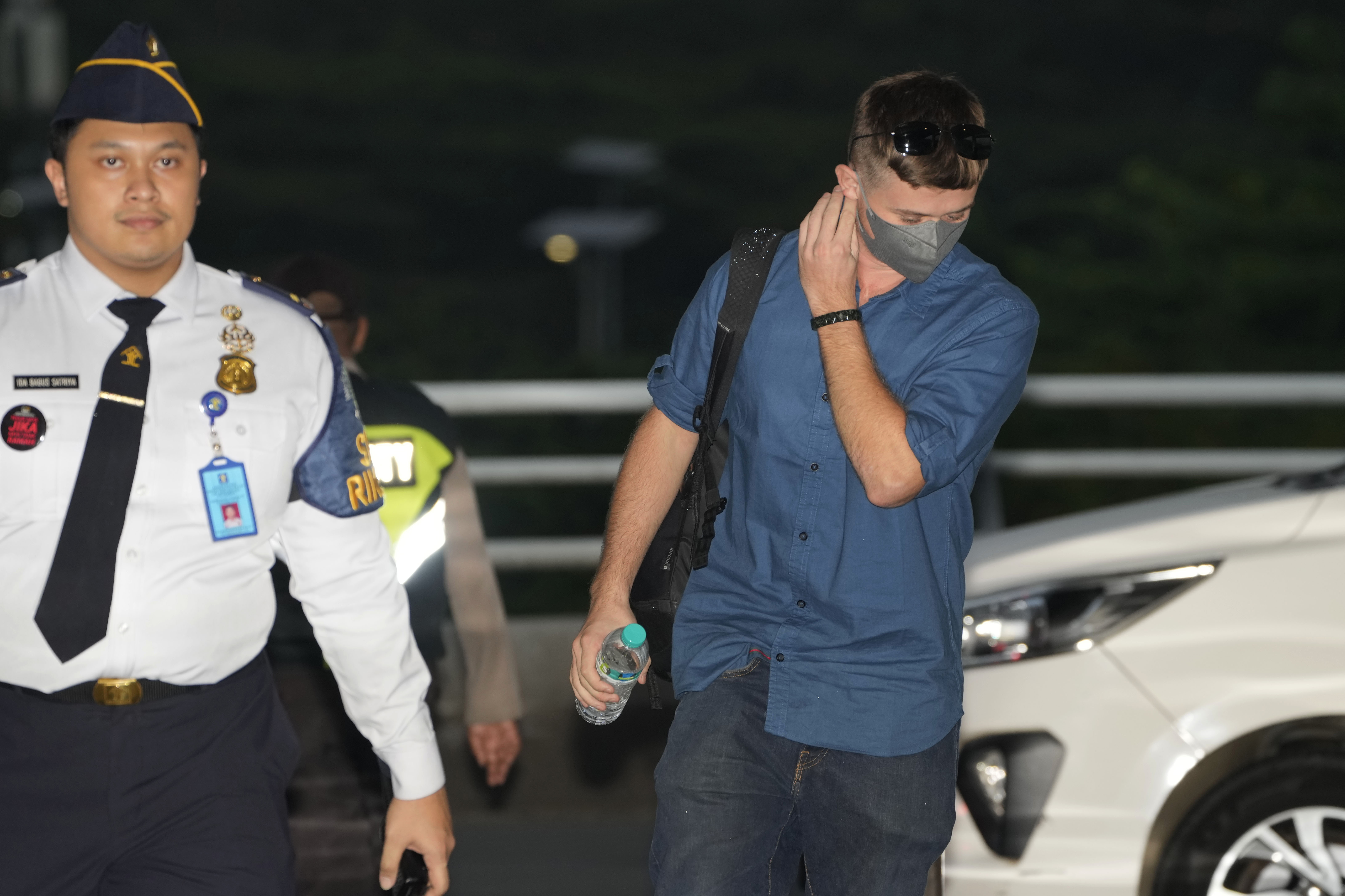 Australian national Bodhi Mani Risby-Jones from Queensland, center, walks with an immigration officer upon arrival at Soekarno-Hatta International Airport in Tangerang, Indonesia, Saturday, June 10, 2023. 