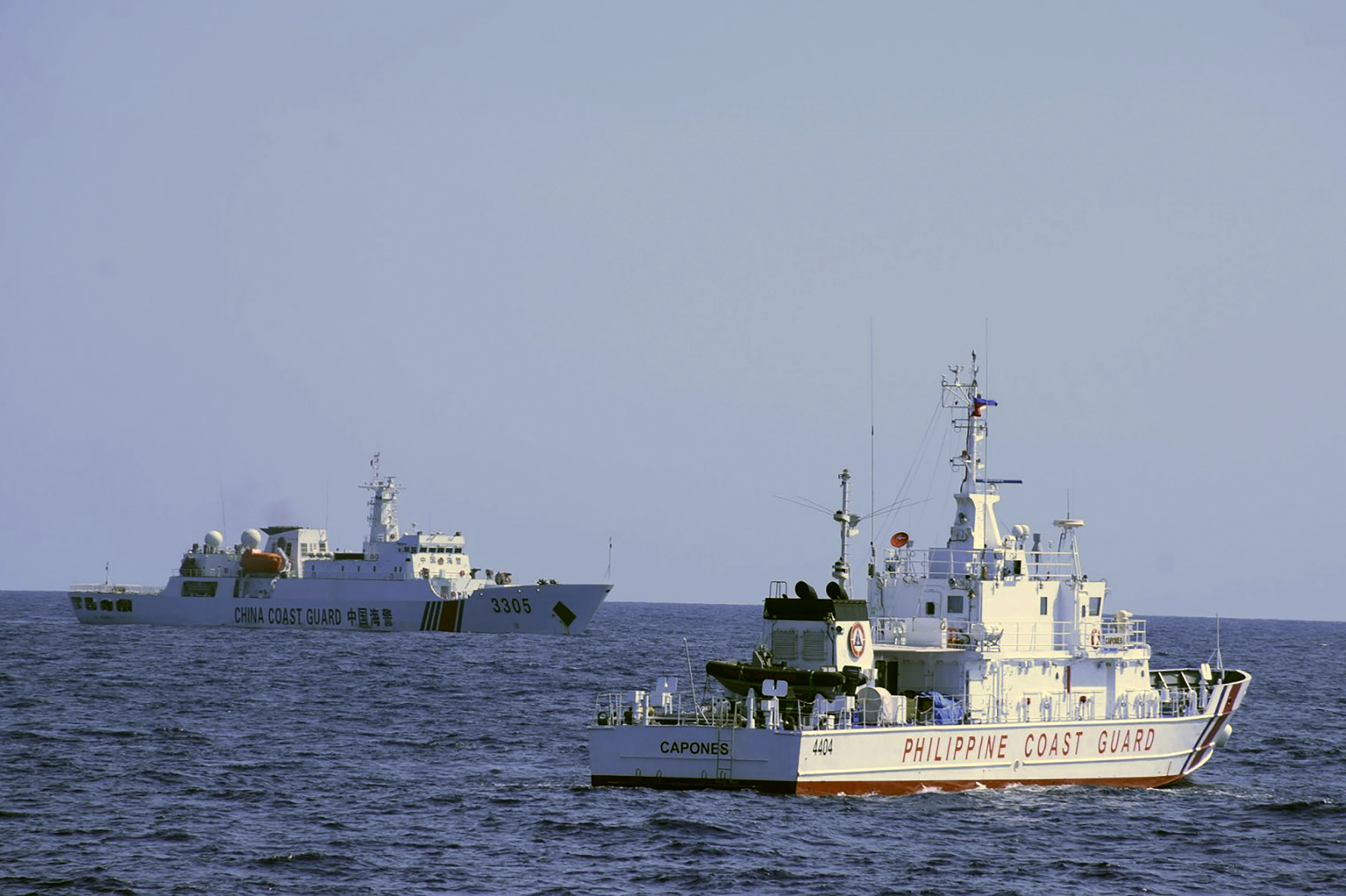 In this photo provided by the Philippine Coast Guard, a Chinese Coast Guard ship sails near a Philippine Coast Guard vessel during its patrol at Bajo de Masinloc, 124 nautical miles west of Zambales province, northwestern Philippines on March 2, 2022. 