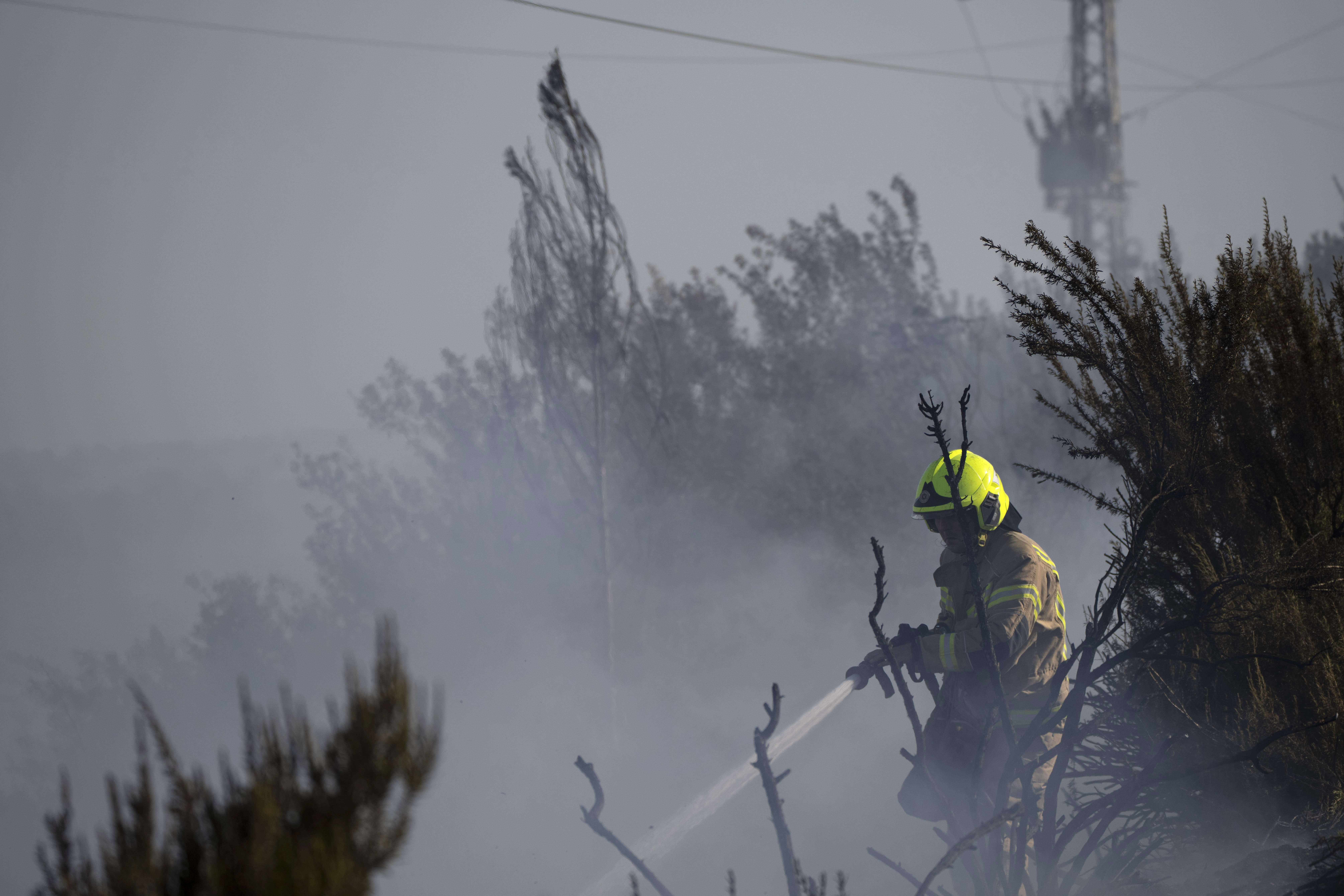 A firefighter works to extinguish a fire after a rocket, fired from Lebanon, hit an area next to a road near Kiryat Shmona, northern Israel, Saturday, Oct. 5, 2024 