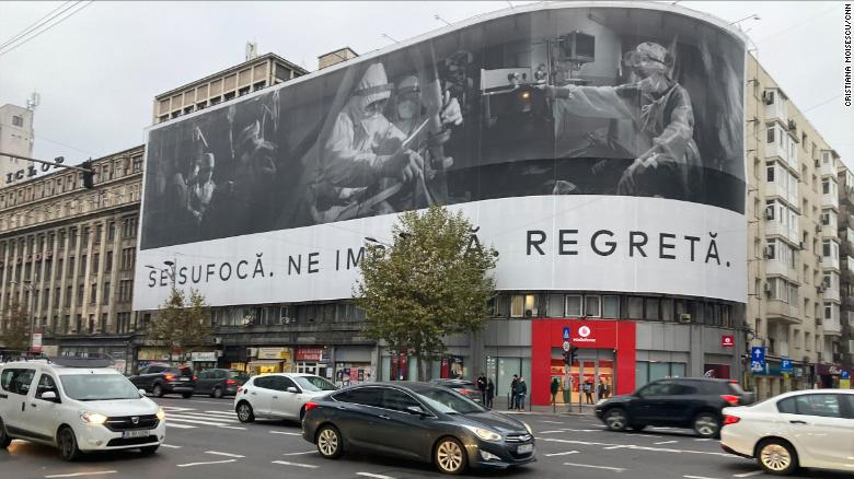 A banner in Bucharest shows medics working on COVID-19 patients with this message: "They're suffocating. They're begging us. They're regretting."