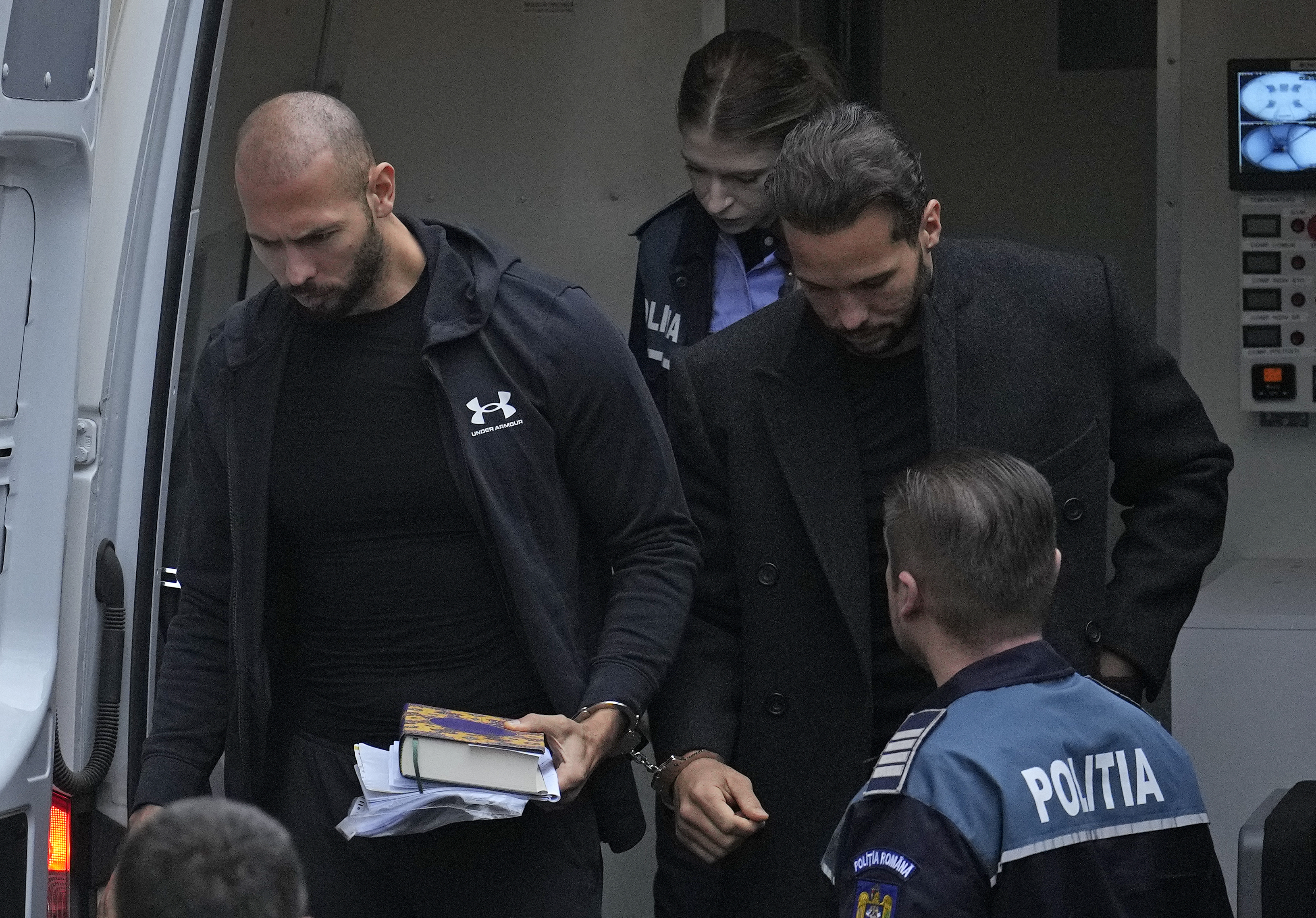 Andrew Tate, right, and his brother Tristan, left, are brought by police officers to the Court of Appeal, in Bucharest, Romania, Tuesday, Jan.10, 2023. Andrew Tate, a divisive social media personality and former professional kickboxer, was detained last month in Romania on charges of human trafficking and rape, and later arrested for 30 days after a court decision. (AP Photo/Vadim Ghirda)