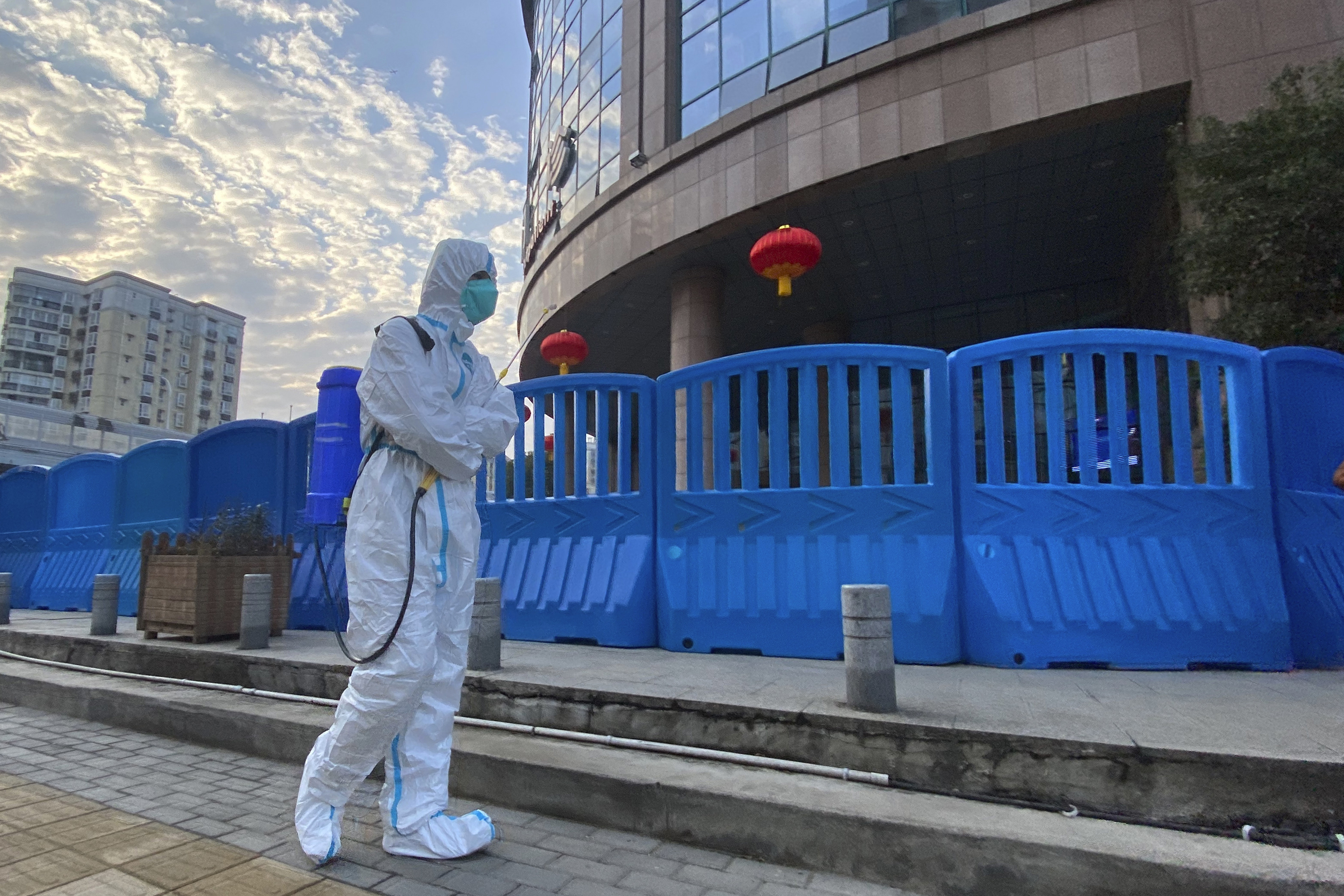 A worker in protectively overalls and carrying disinfecting equipment walks outside the Wuhan Central Hospital, China on Feb. 6, 2021