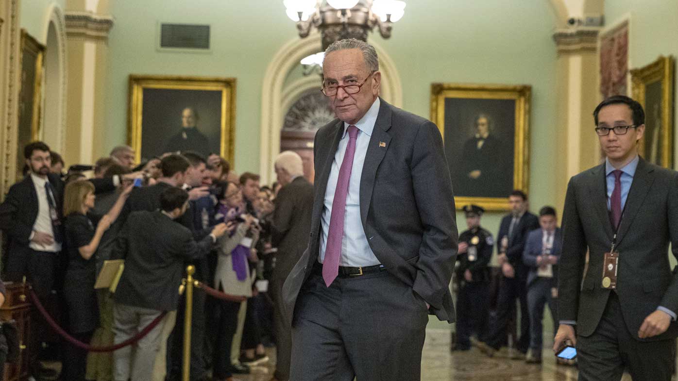 Senate Minority Leader Chuck Schumer walks away from a throng of reporters in the Capitol.