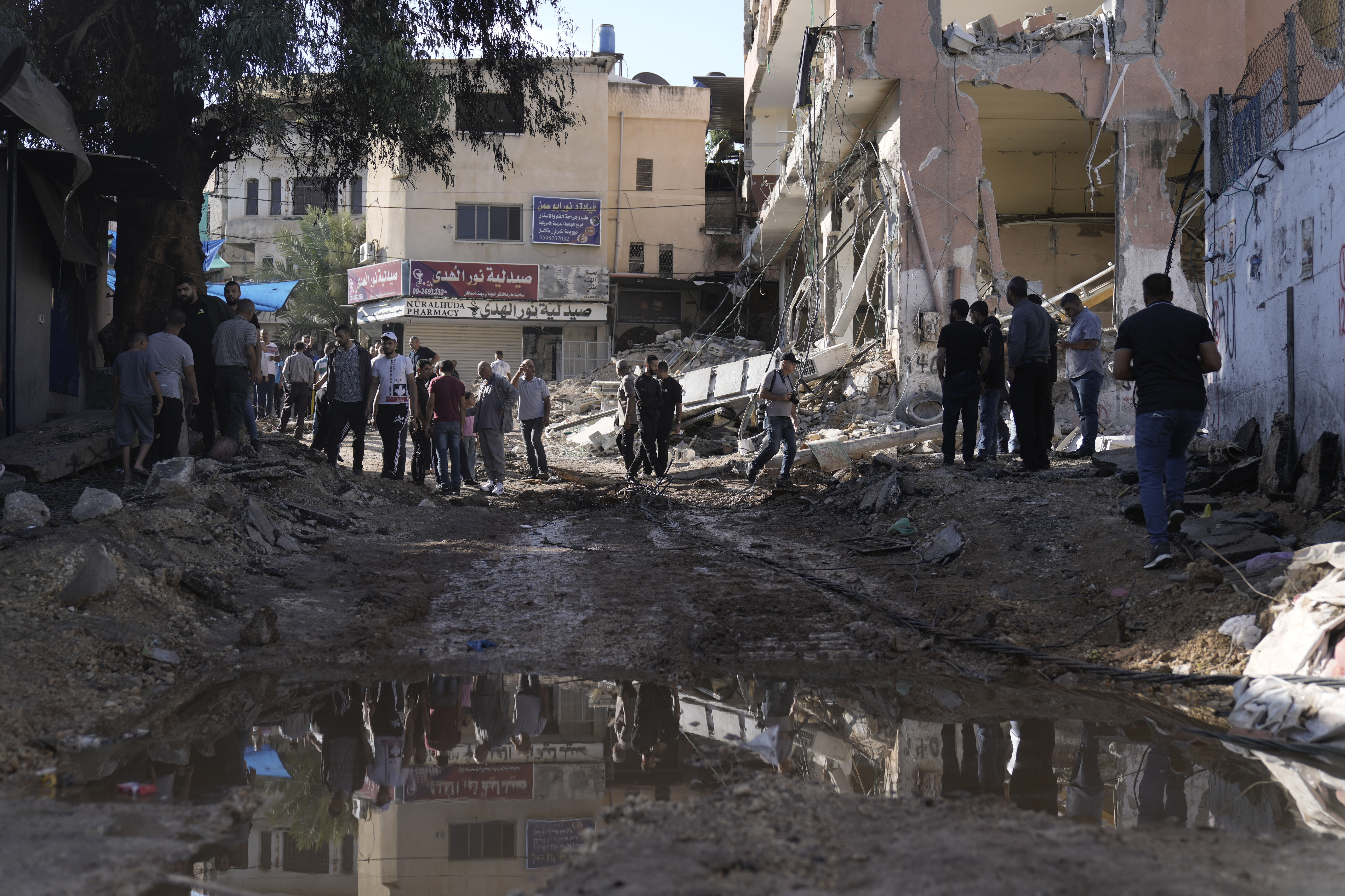 People look at destruction after an Israeli army raid on a Palestinian refugee camp, Nur Shams, in the West Bank, Friday, Oct. 20, 2023. 