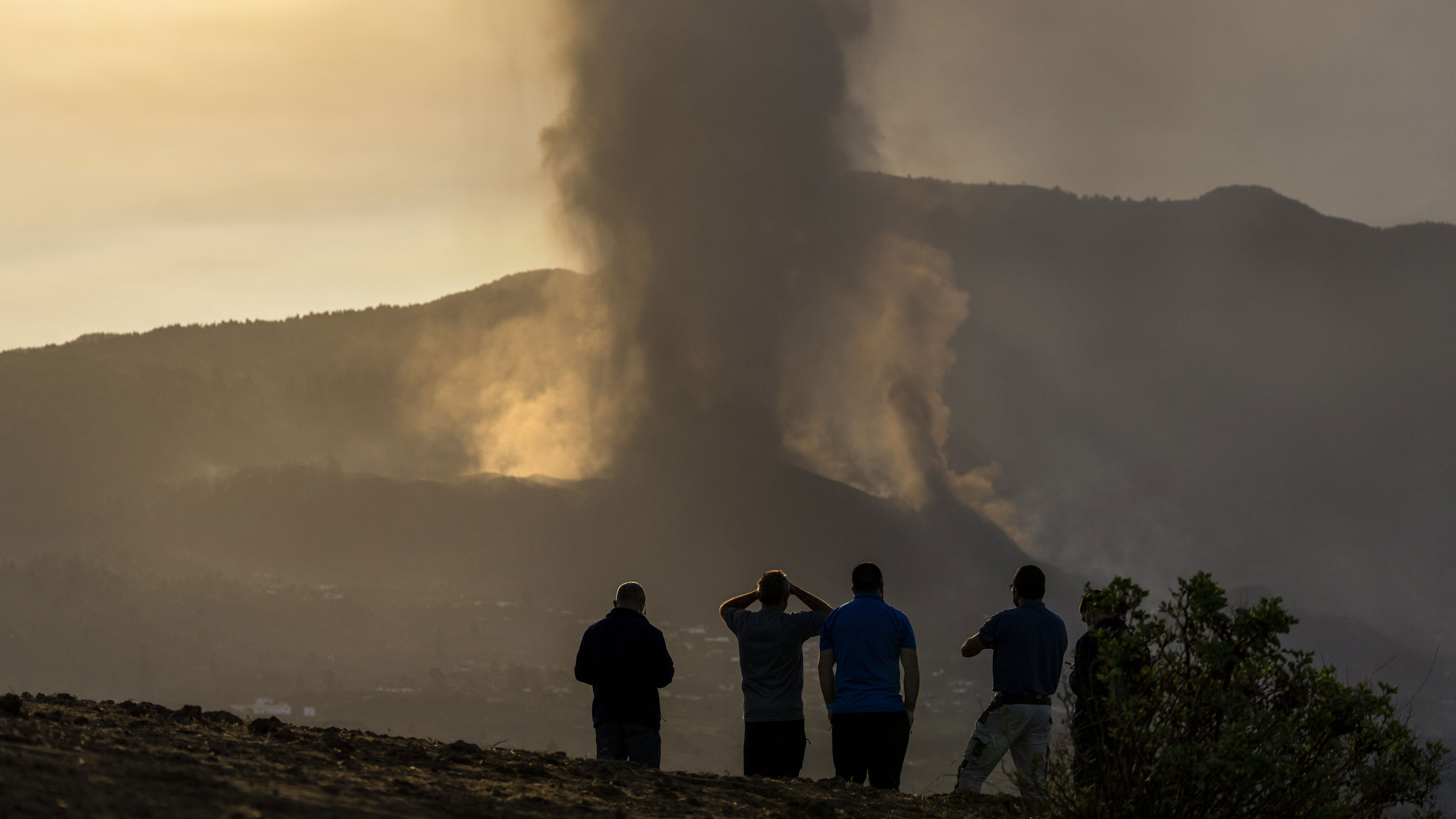 Residents watch from a hill as lava continues to flow from an erupted volcano, on the island of La Palma in the Canaries, Spain.