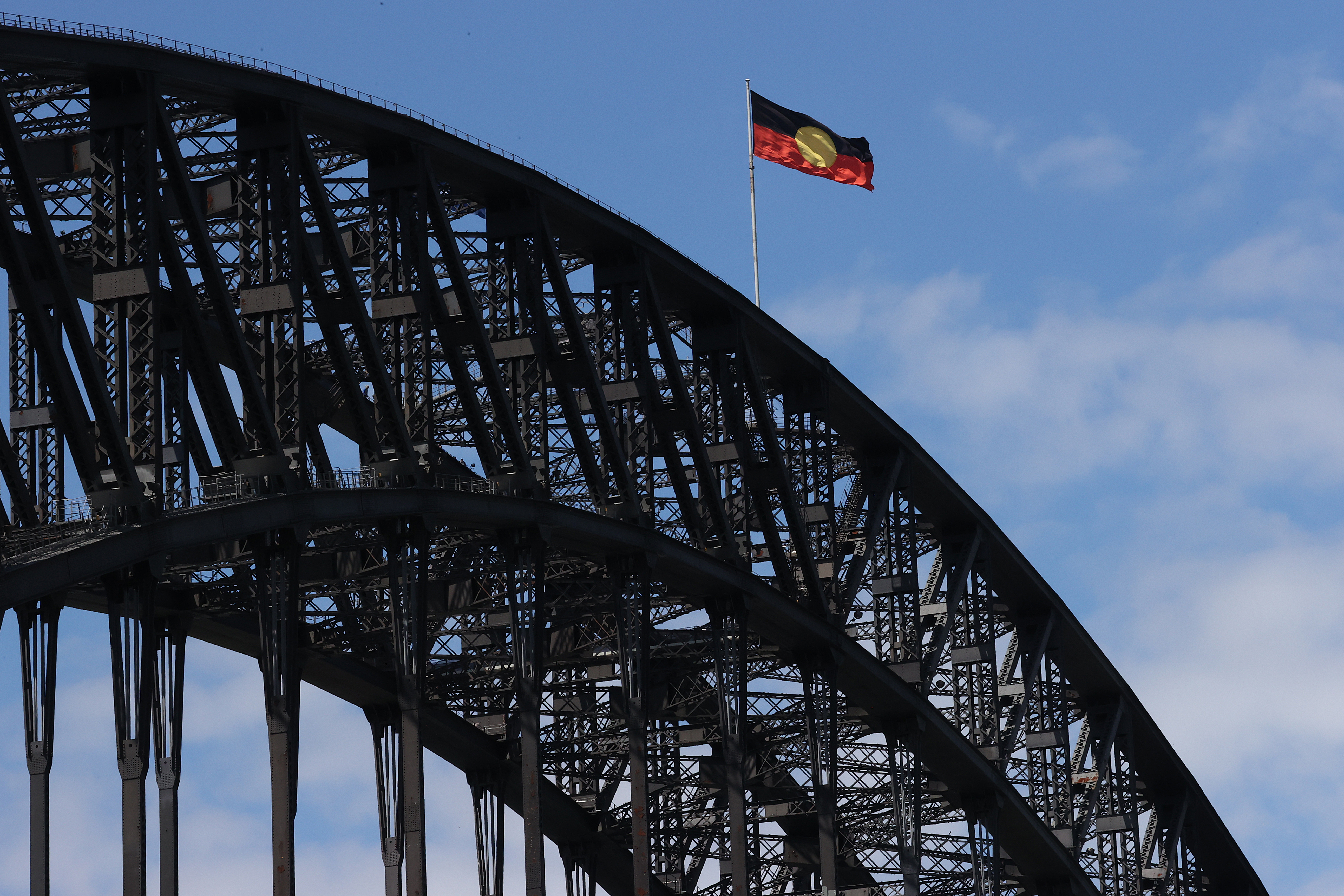 The Australian Aboriginal Flag flies high atop the Sydney Harbour Bridge for the first time since the federal government announced it had paid more than $20 million to Luritja artist Harold Thomas and licence holders to secure copyright for the iconic flag. Pictured on Australia Day 26th January, 2022. Photo: Dylan Coker/The Sydney Morning Herald