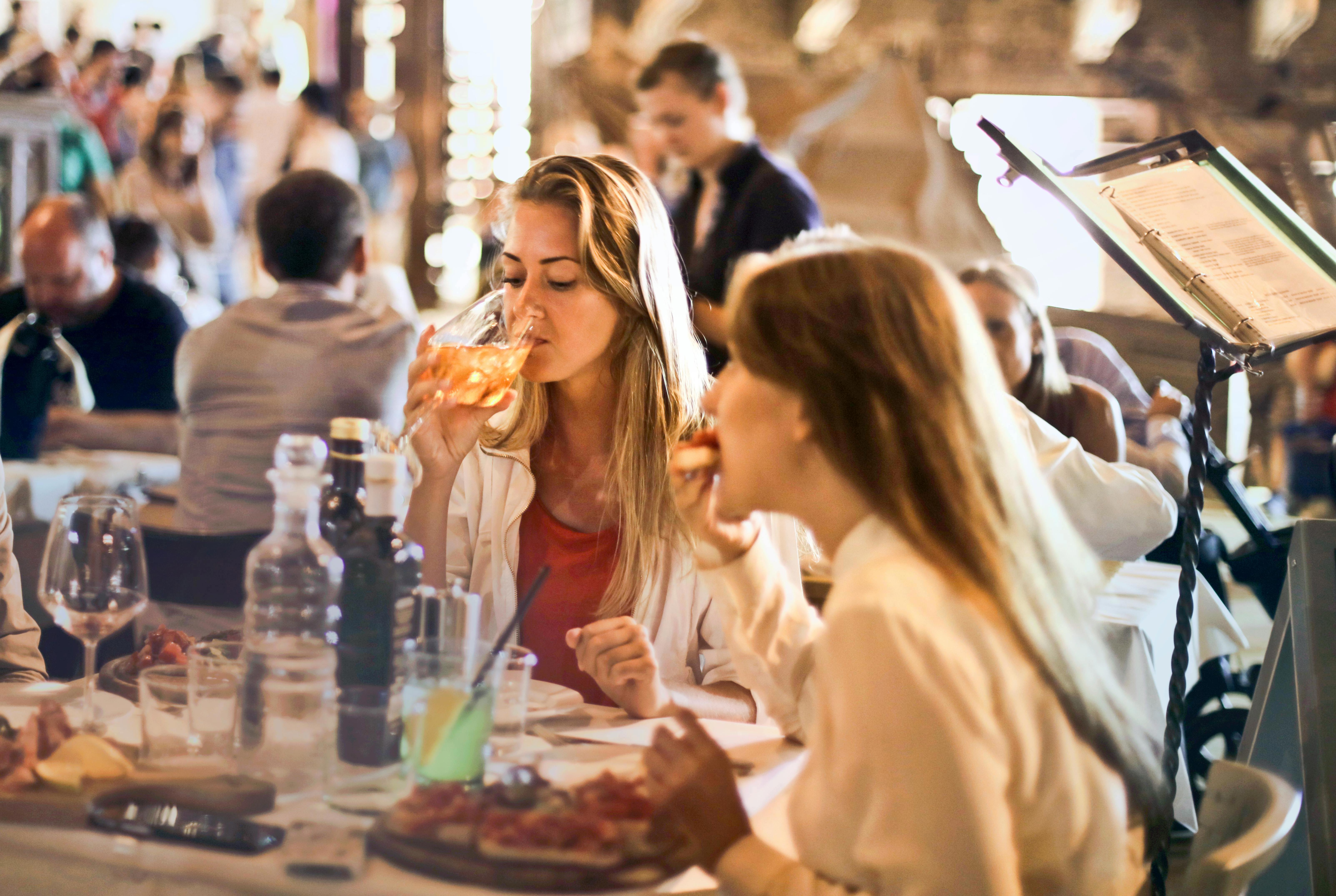 Stock image of two women eating and drinking wine.