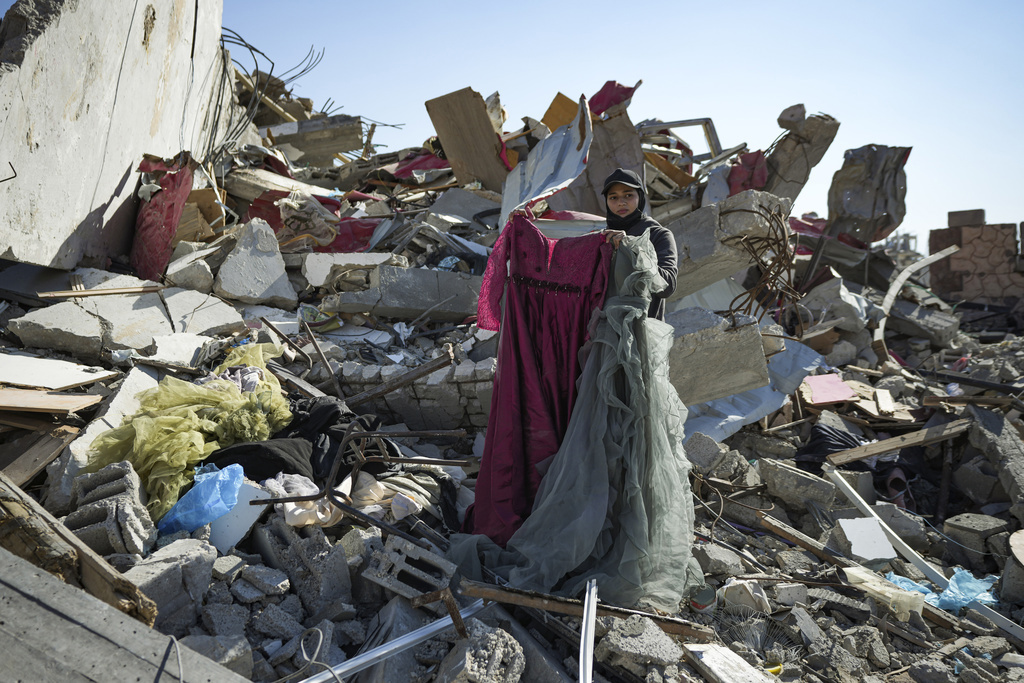 Nour Abu Al Zamar salvage items from under the rubble of her destroyed family home, in Rafah, southern Gaza Strip, Tuesday, Jan. 21, 2025, days after the ceasefire deal between Israel and Hamas came into effect. (AP Photo/Abdel Kareem Hana)