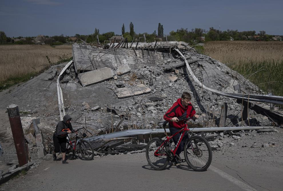 Teenagers on bicycles pass a bridge destroyed by shelling near Orihiv, Ukraine