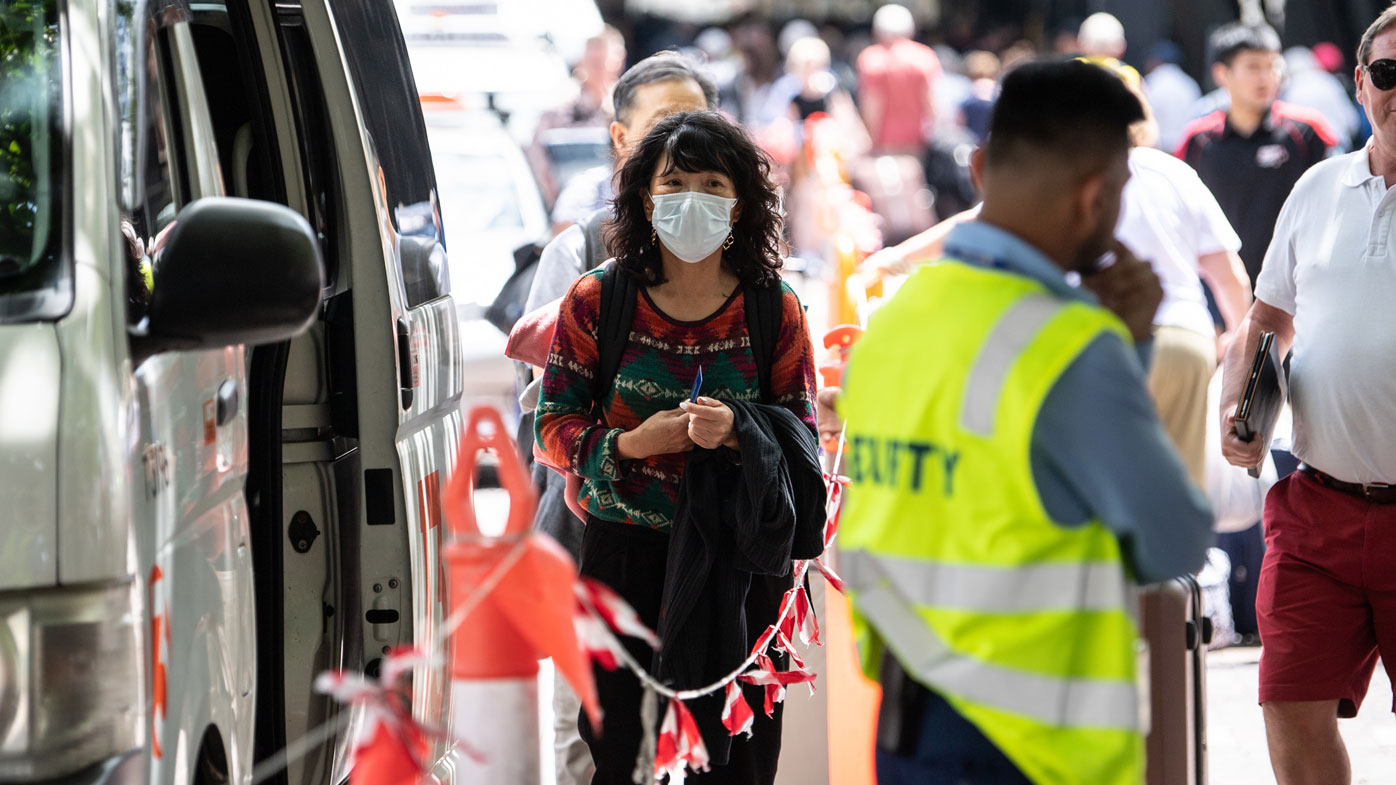 A woman wearing a face mask seen near the Overseas Passenger Terminal where the Norwegian Jewel cruise ship is moored at Circular Quay in Sydney, Friday, February 14, 2020.