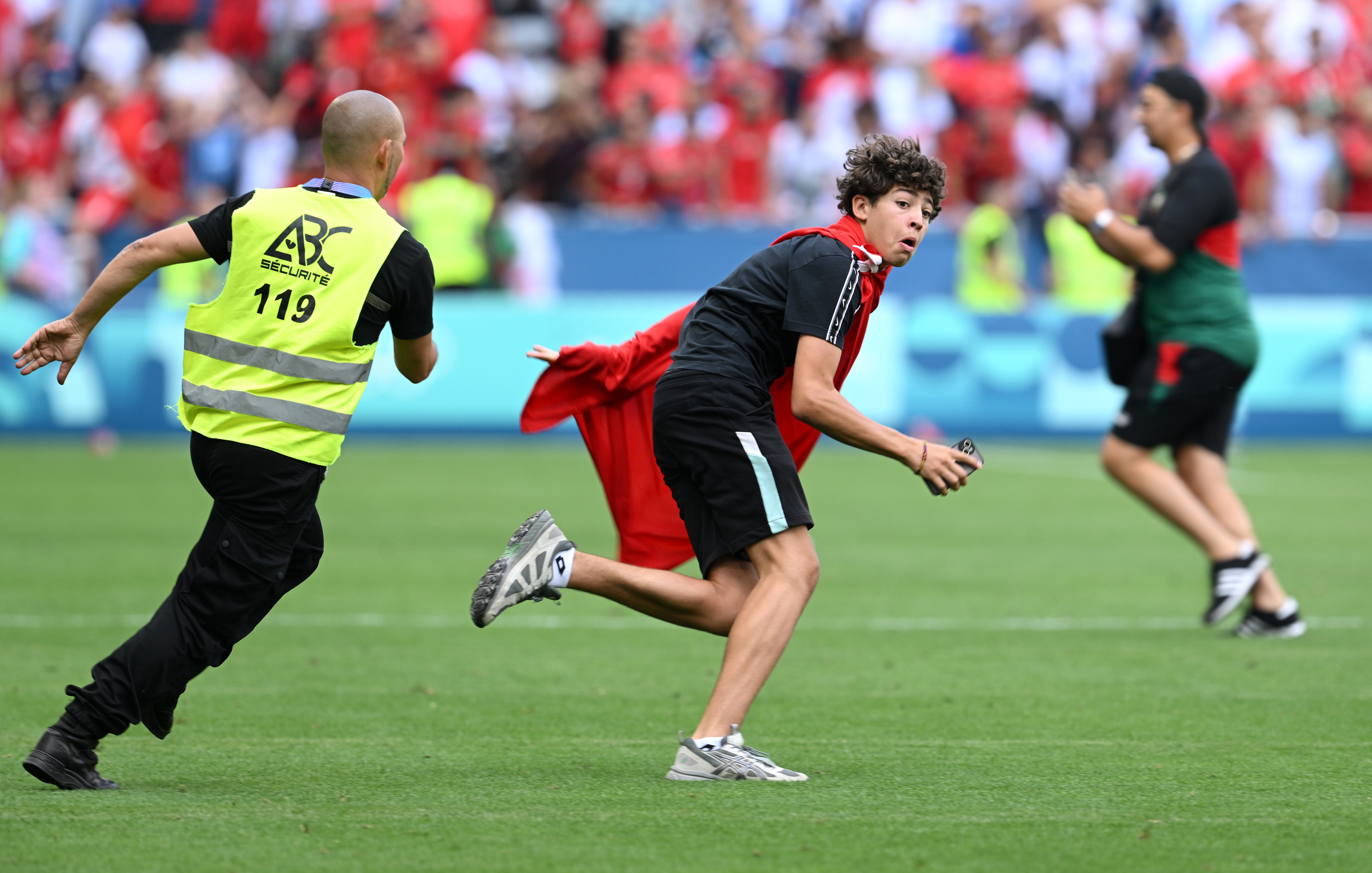 A pitch invader is chased by a steward.