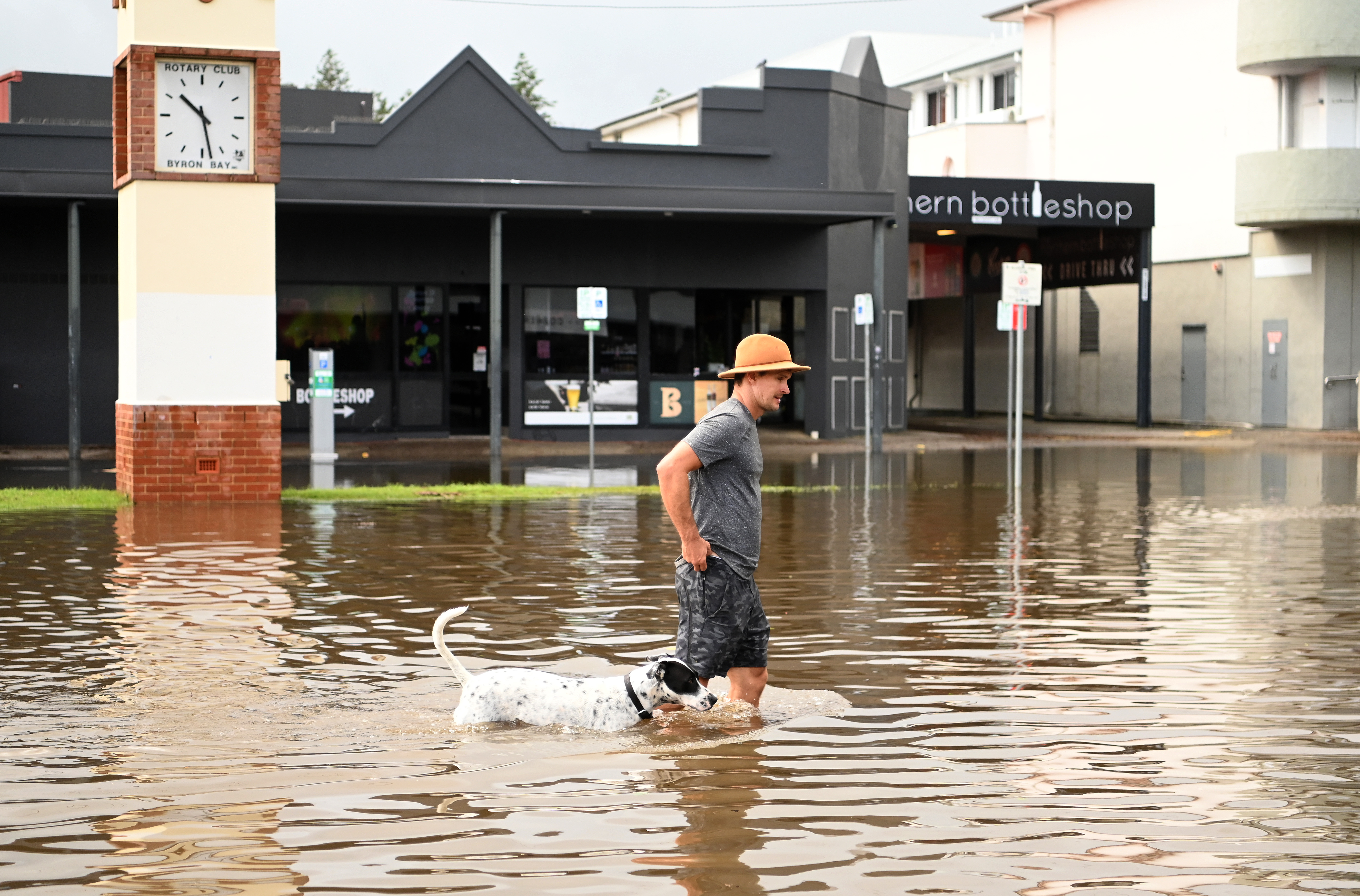 A man and his dog walk through floodwater on March 30, 2022 in Byron Bay, Australia. Evacuation orders have been issued for towns across the NSW Northern Rivers region, with flash flooding expected as heavy rainfall continues. It is the second major flood event for the region this month. (Photo by Dan Peled/Getty Images)