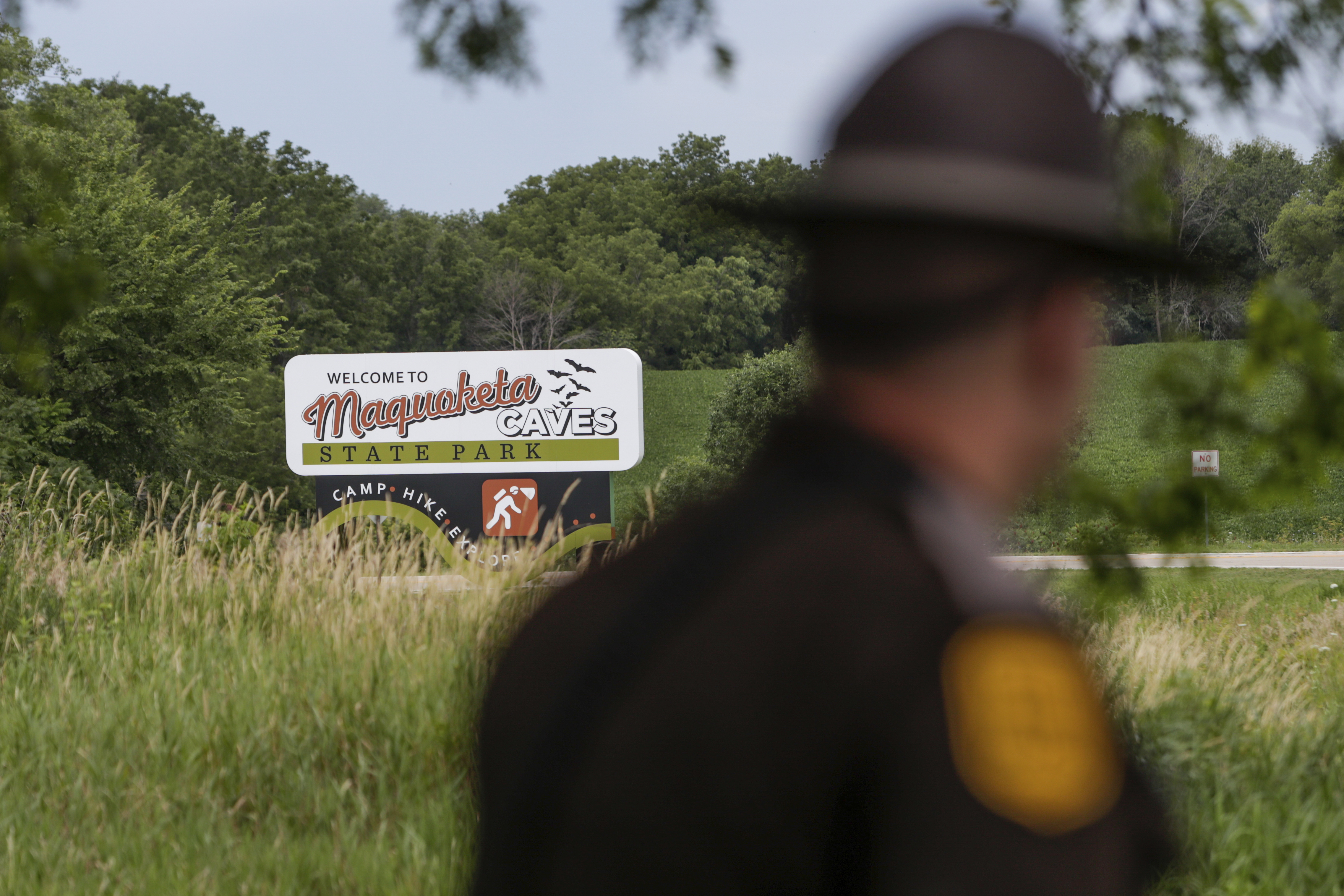 Un patrullero del estado de Iowa pasa junto a un letrero del parque estatal Maquoketa Caves mientras la policía investiga un tiroteo que dejó varias personas muertas, el viernes 22 de julio de 2022, en Maquoketa, Iowa. 