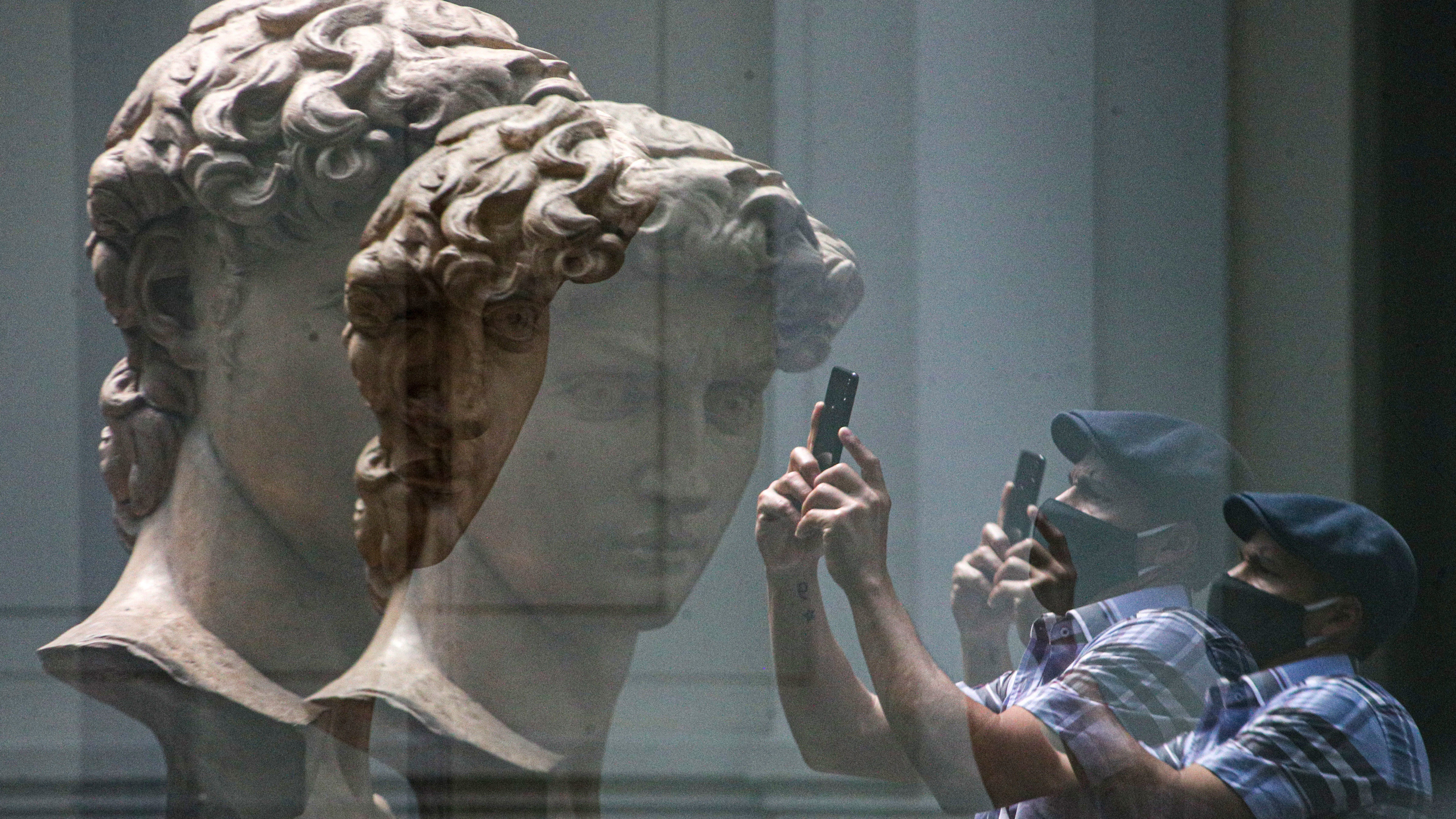 Un visitante se refleja en un cristal mientras toma una fotografía de una réplica de la cabeza de la escultura de Miguel Ángel. "David" en el Museo Nacional de Bellas Artes.