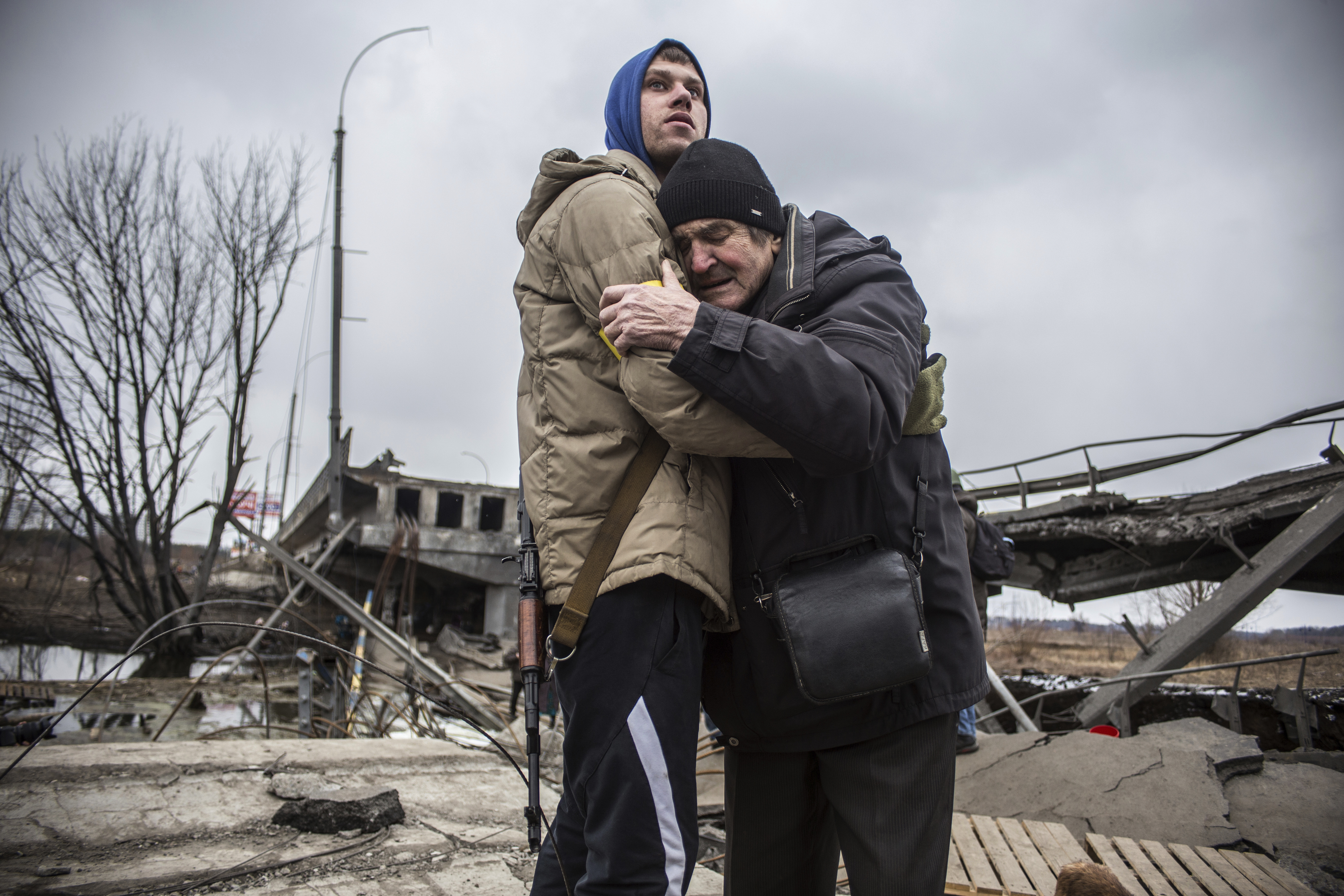 A Ukrainian Territorial Defence Forces member hugs a resident who leaves his home town following Russian artillery shelling in Irpin, on the outskirts of Kyiv, Ukraine, Wednesday, March 9, 2022.