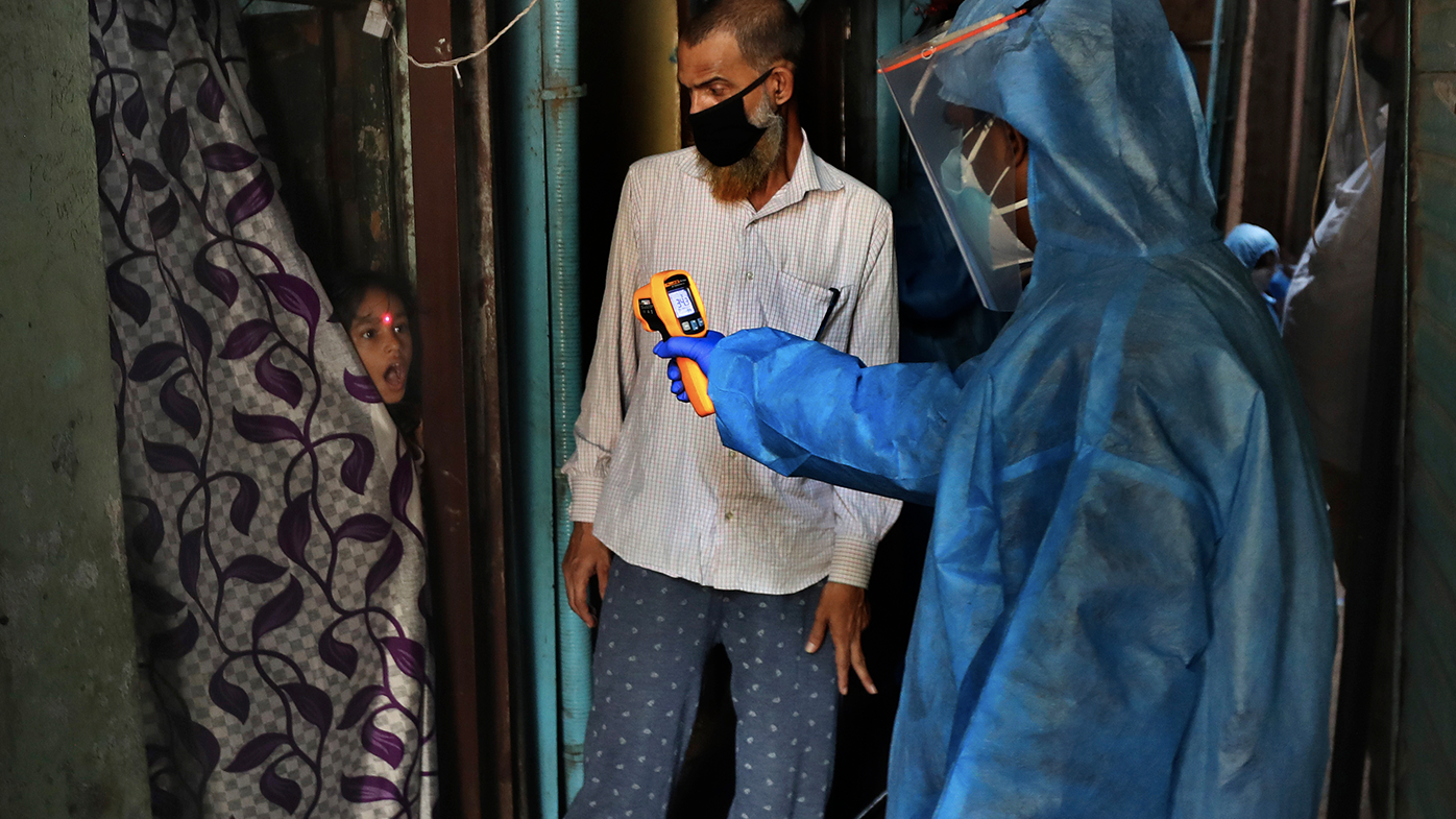 In this Monday, April 13, 2020, file photo, a doctor checks the temperature of a girl in Dharavi, one of Asia's largest slums, during lockdown to prevent the spread of the new coronavirus in Mumbai, India. 