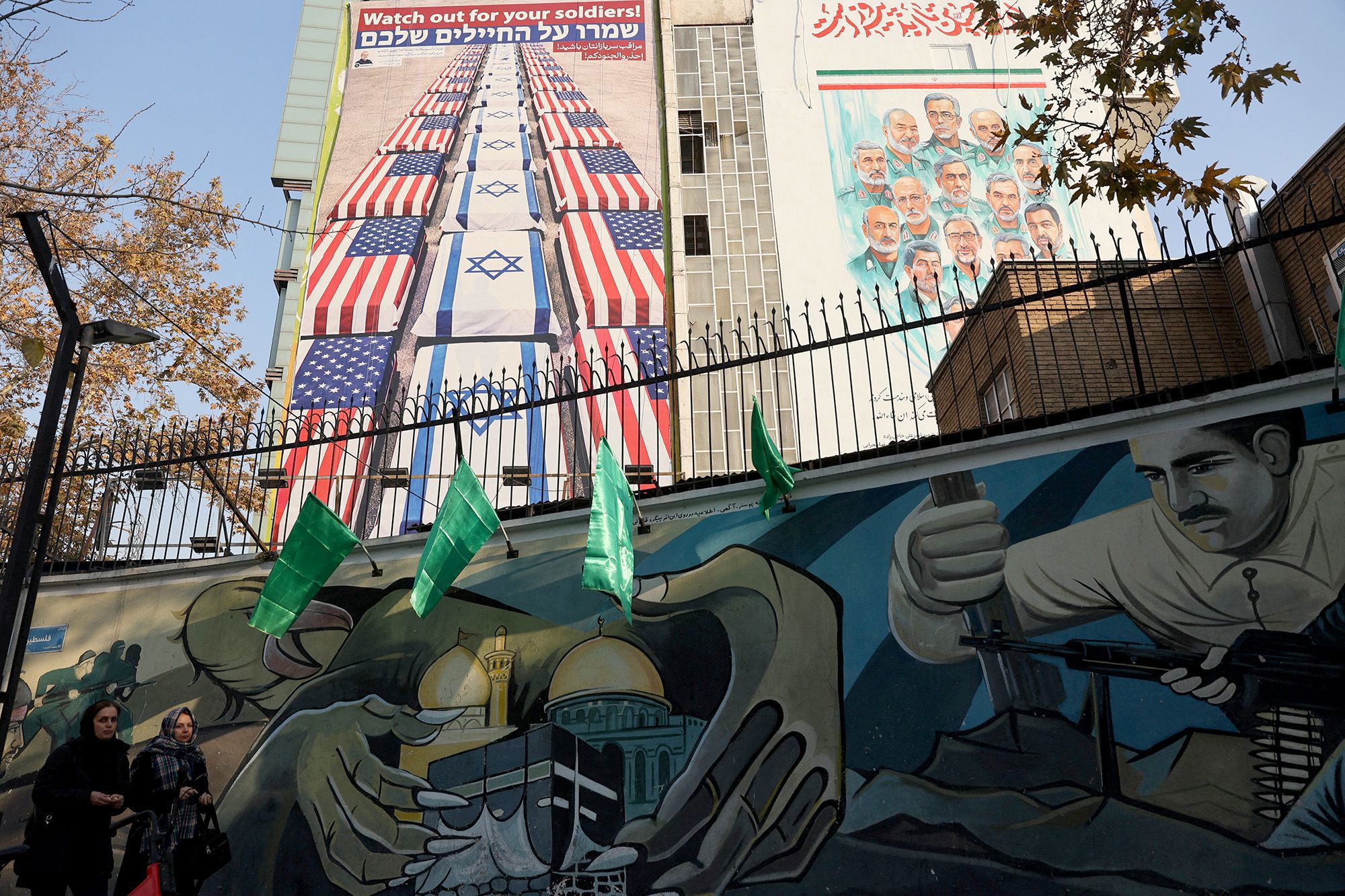 Women walk past an anti-US and anti-Israel billboard displayed on a building in Tehran, Iran on January 4.