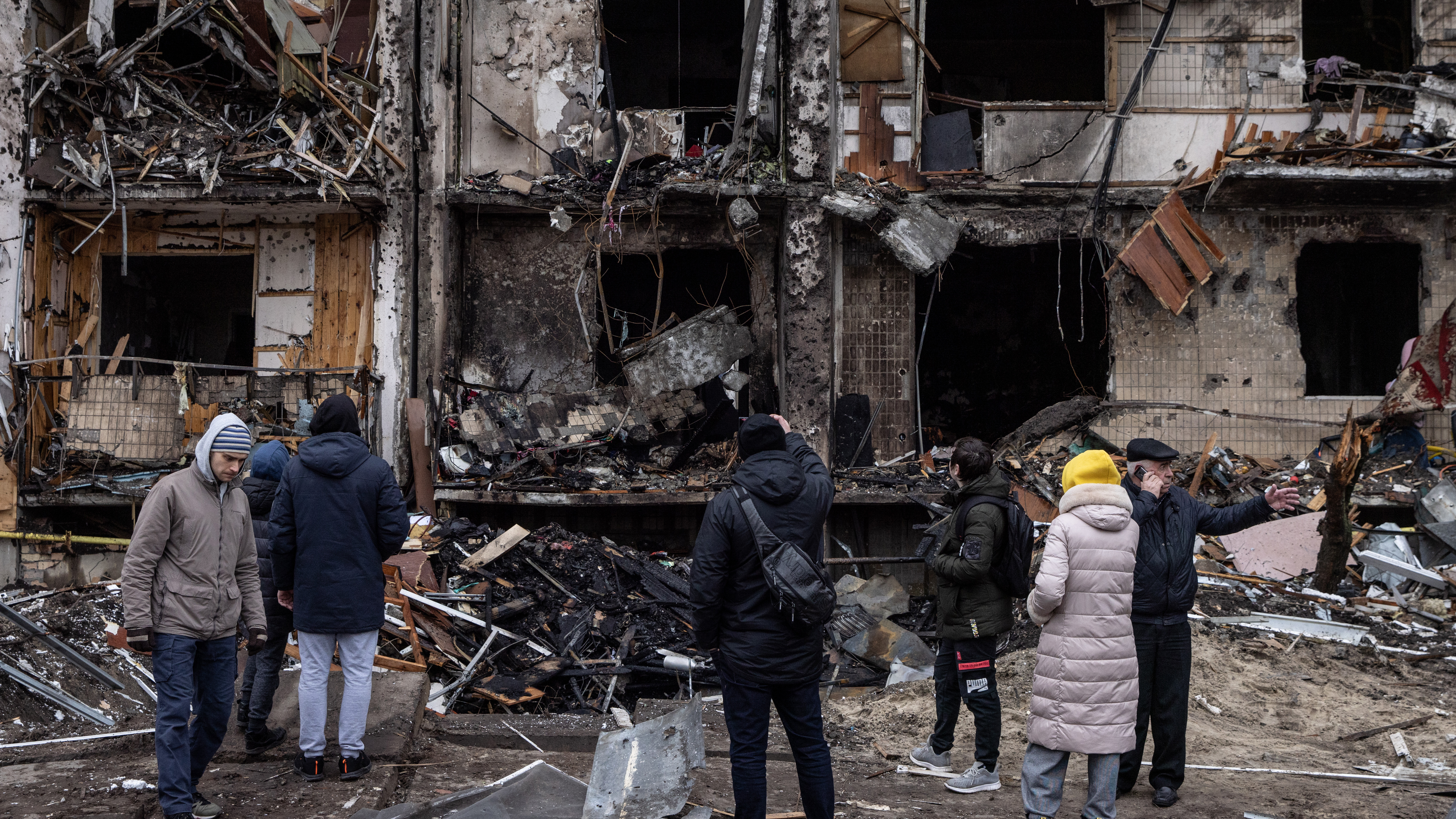 People look at a damaged residential block hit by an early morning missile strike in Kyiv.