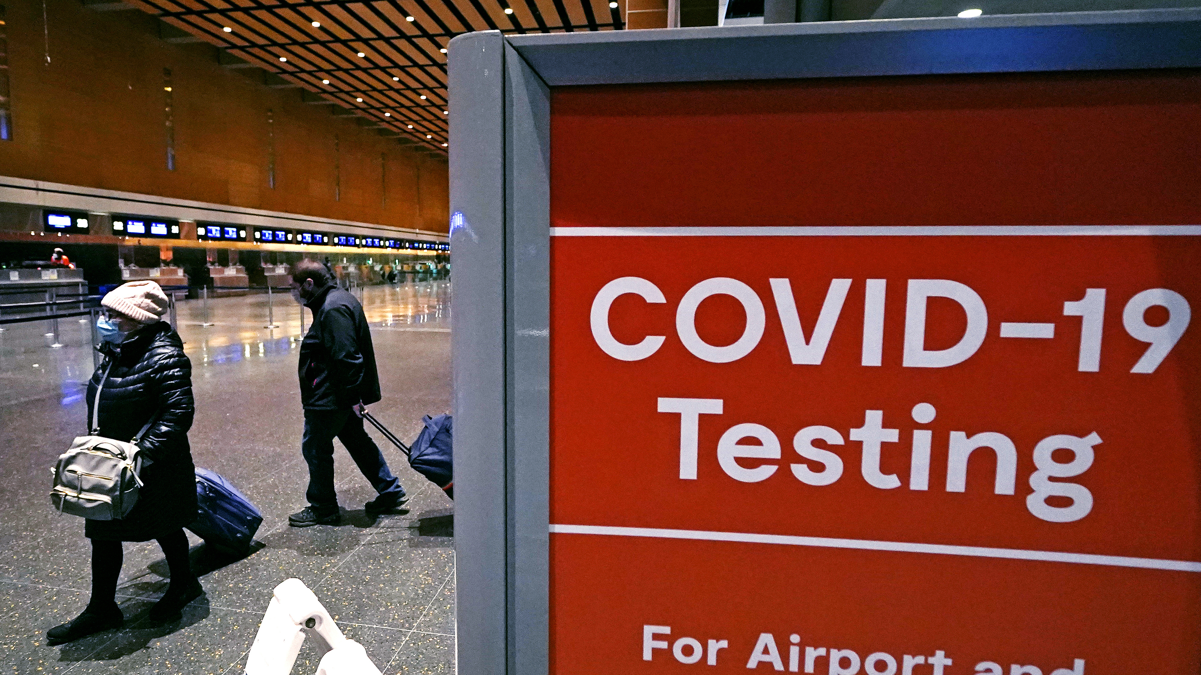 ARCHIVO - Los viajeros pasan un letrero cerca de un sitio de prueba de COVID-19 en la Terminal E del Aeropuerto Logan, el 21 de diciembre de 2021, en Boston. dentro de un día antes de abordar sus vuelos, facilitando uno de los últimos mandatos gubernamentales restantes destinados a contener la propagación del coronavirus.  (Foto AP/Charles Krupa, archivo)