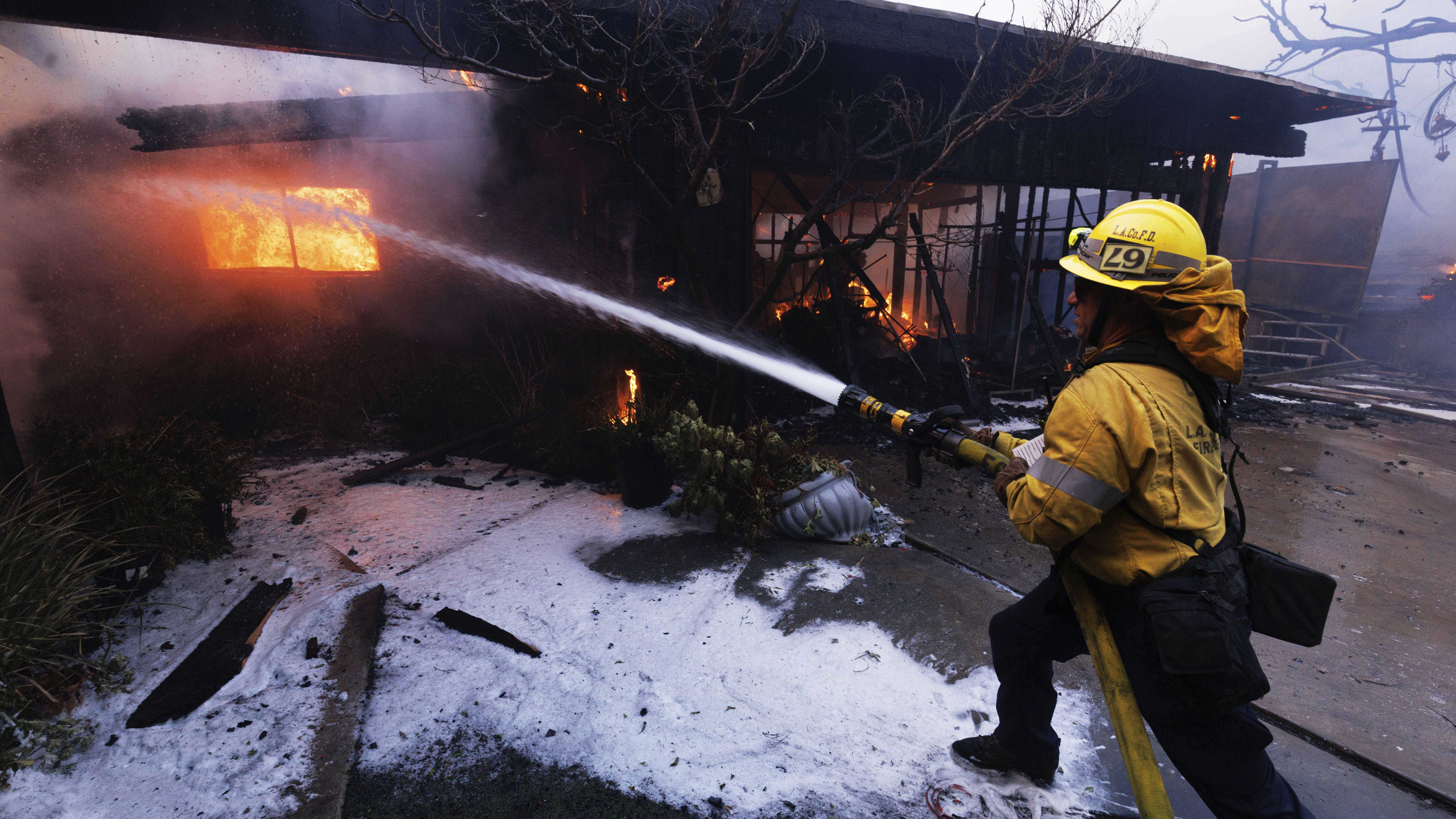 A firefighter tries to extinguish a fire as it damages a property in the Pacific Palisades neighbourhood of Los Angeles.