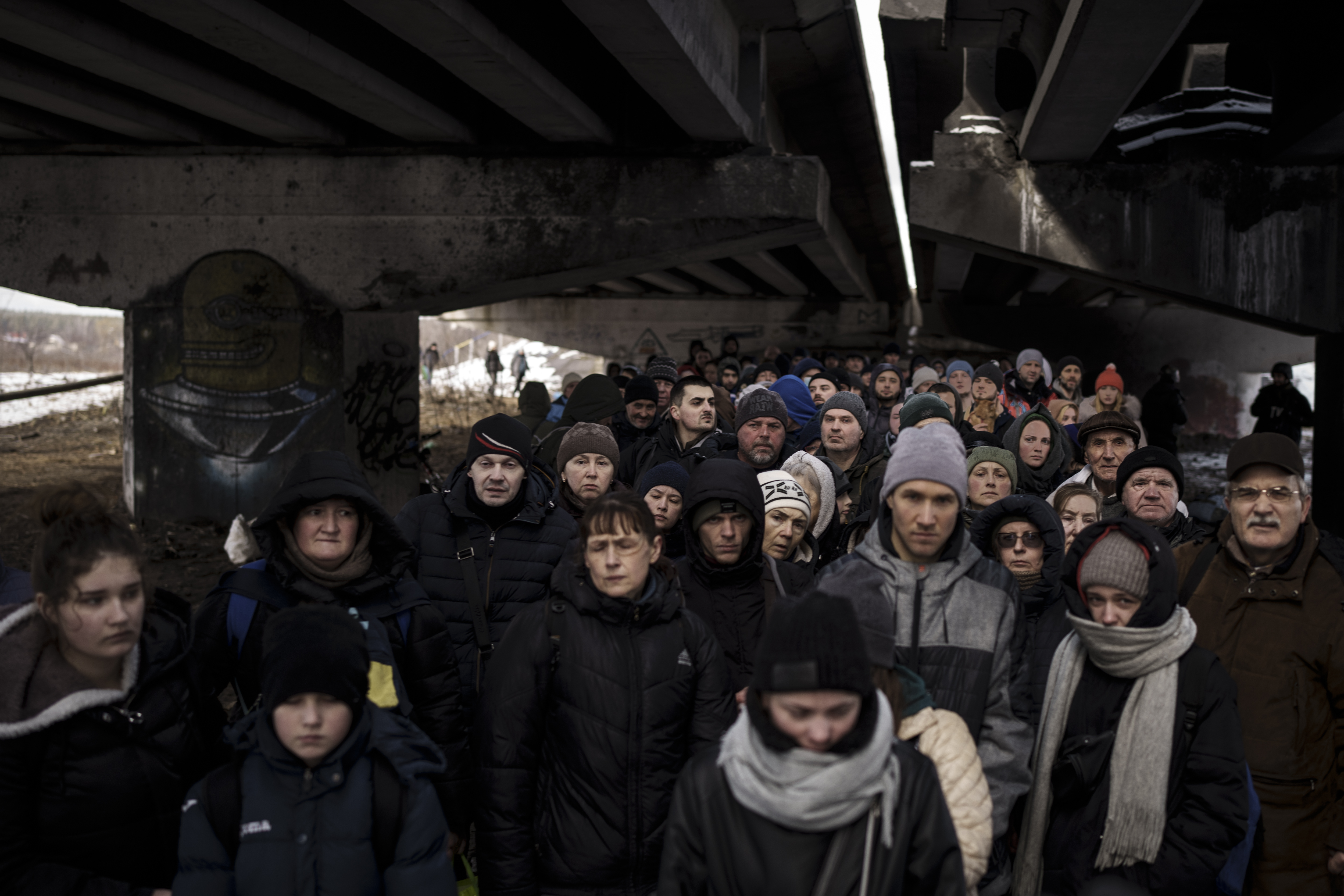 Ukrainians crowd under a destroyed bridge as they try to flee crossing the Irpin river in the outskirts of Kyiv, Ukraine, Tuesday, March 8, 2022.