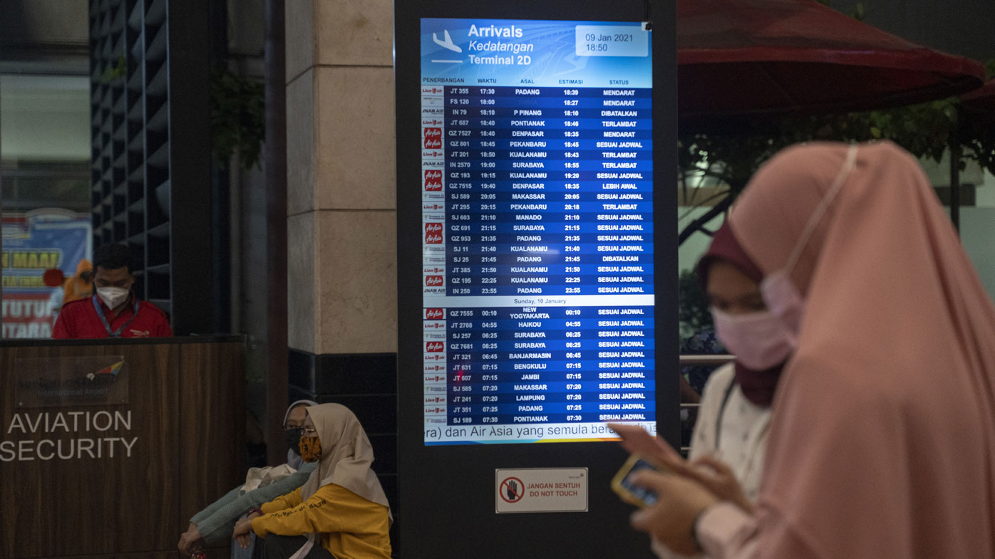 People watch a schedule board at the Crisis centre in Soekarno Hatta Airport, on January 09, 2021 in Jakarta, Indonesia