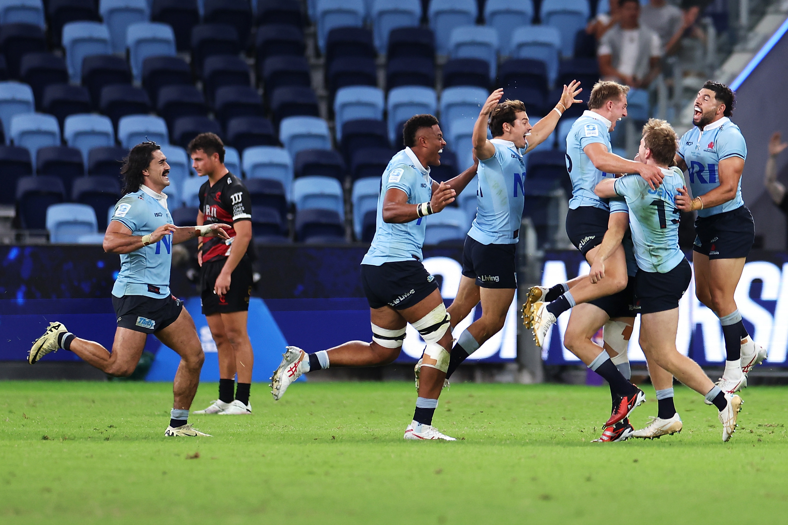 The Waratahs celebrate with Will Harrison of the Waratahs after he kicked the winning field goal in golden point during the round eight Super Rugby Pacific match between NSW Waratahs and Crusaders.