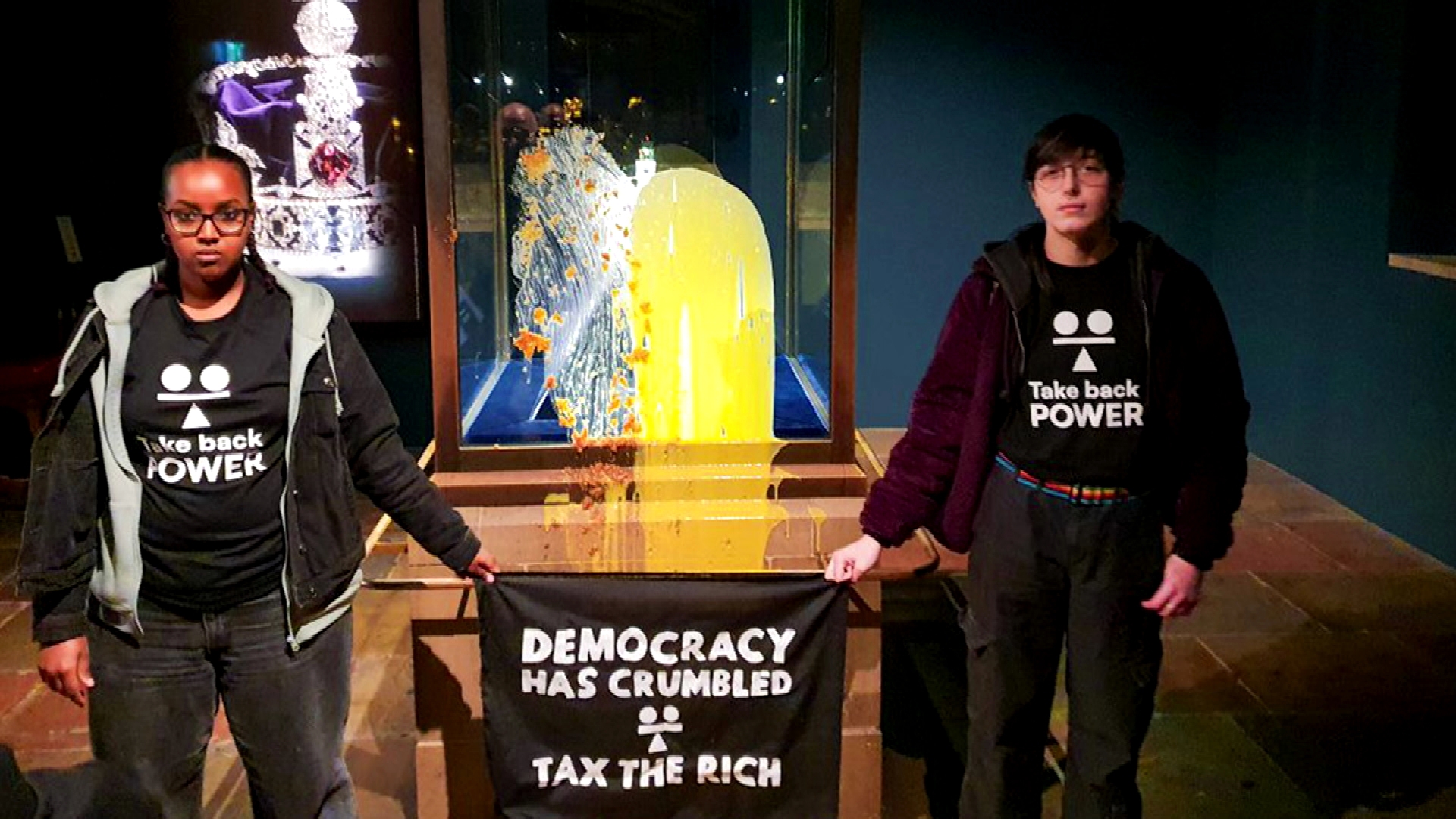 The protesters held a banner saying "democracy has crumbled, tax the rich." They threw custard and apple crumble on the Crown Jewels at the Tower of London.