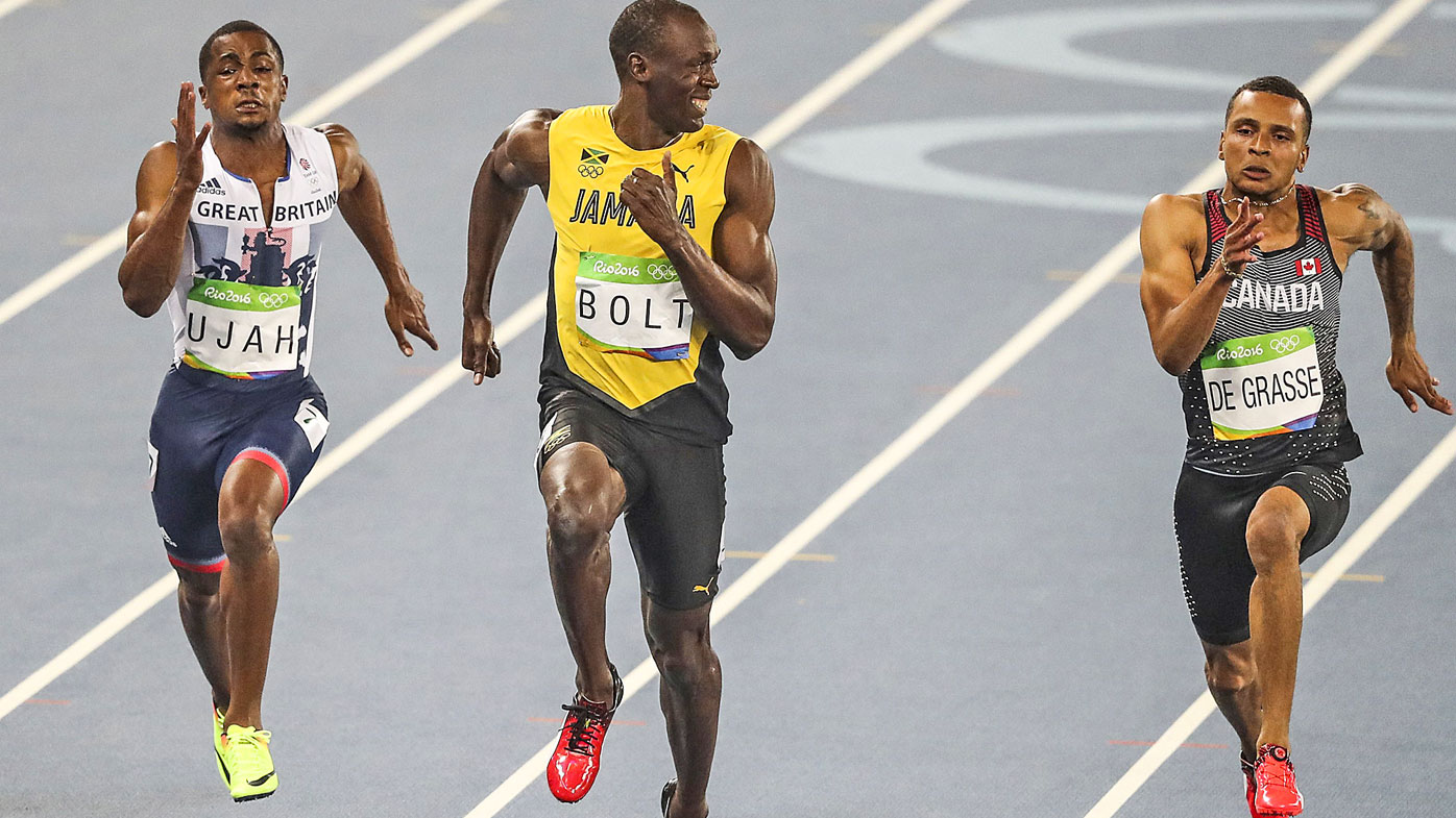 Usain Bolt of Jamaica (C) smiles as he looks at Canada's Andre De Grasse (R) in the Men's 100 metre semifinal of the Rio 2016 Olympic Games