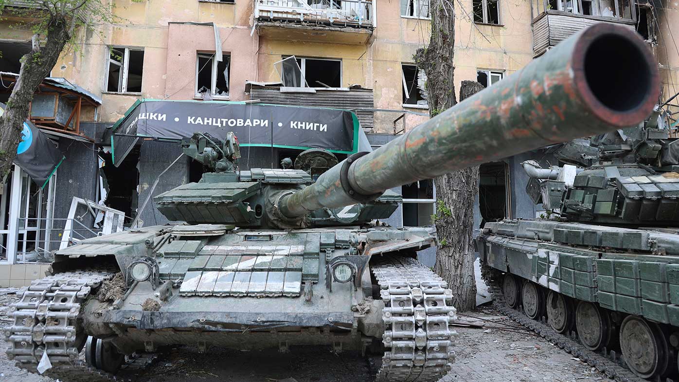 Tanks of Donetsk People's Republic militia stand next to a damaged apartment building in Mariupol.