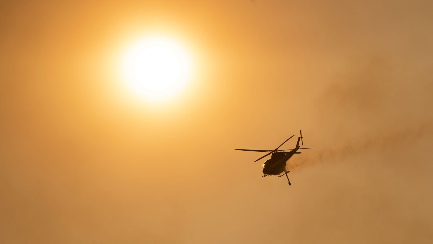 A water-bombing helicopter over Mount Tennant as the fire front of the Orroral Valley fire creeps through the Namadgi National Park on January 30, 2020 in Canberra, Australia. 